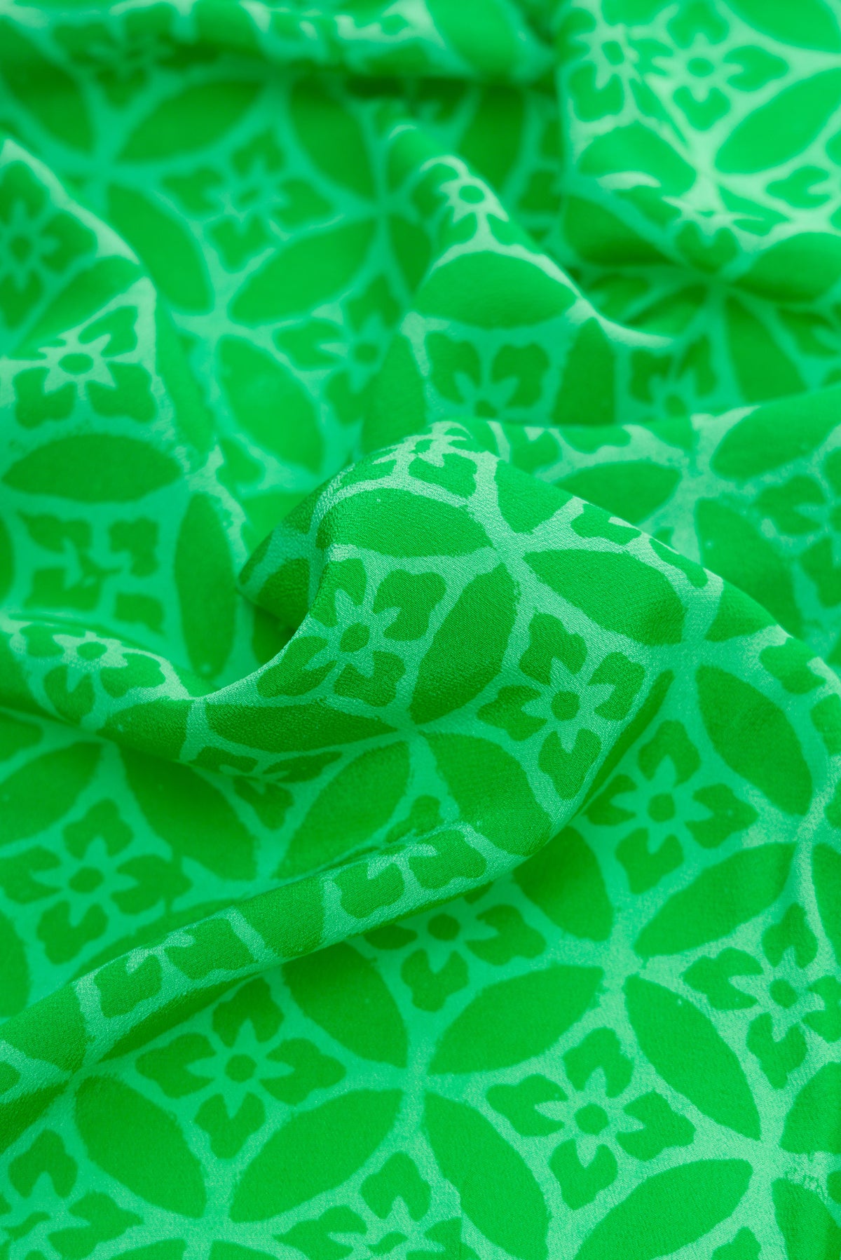 Close up of Parrot Green Dual Tone Mysore Crepe Saree with Printed design on the body and Printed Border.  displaying folds