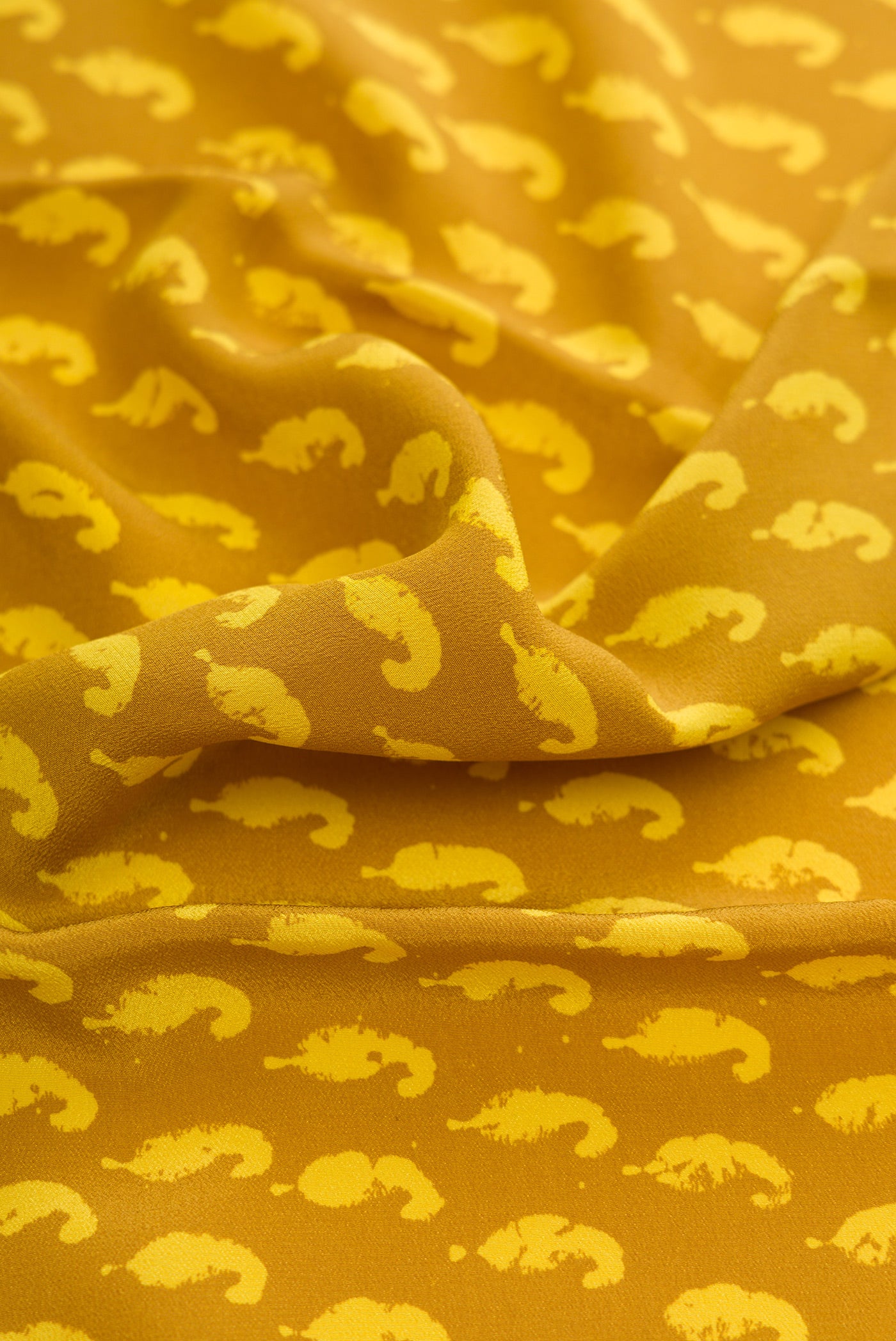 Close up of Mustard Dual Tone Mysore Crepe Saree with Printed design on the body and Printed Border.  displaying folds