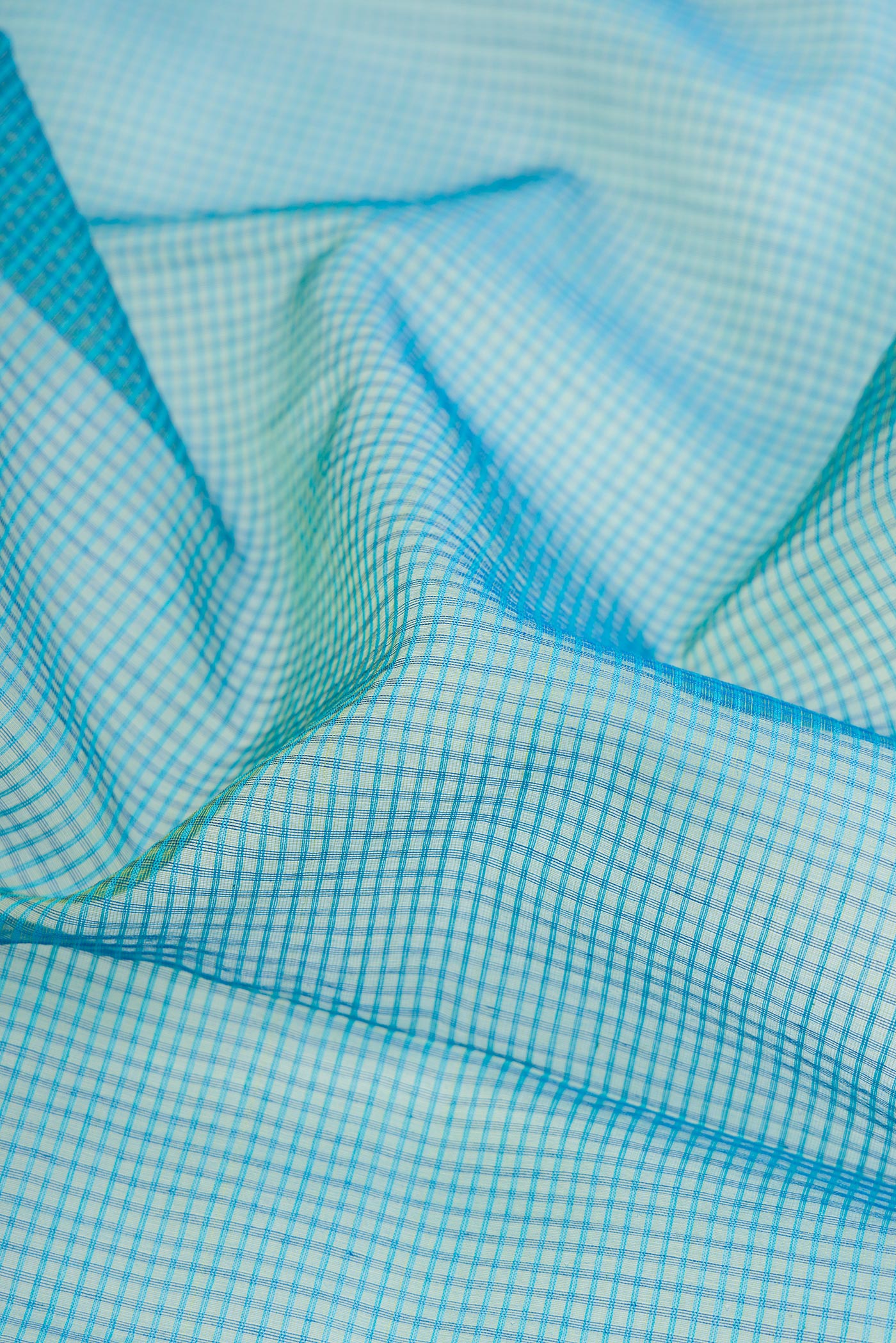 Close up of Peacock Blue Dual Tone Maheshwari Silk Cotton Saree with Checked design on the body and Zari Border.  displaying folds