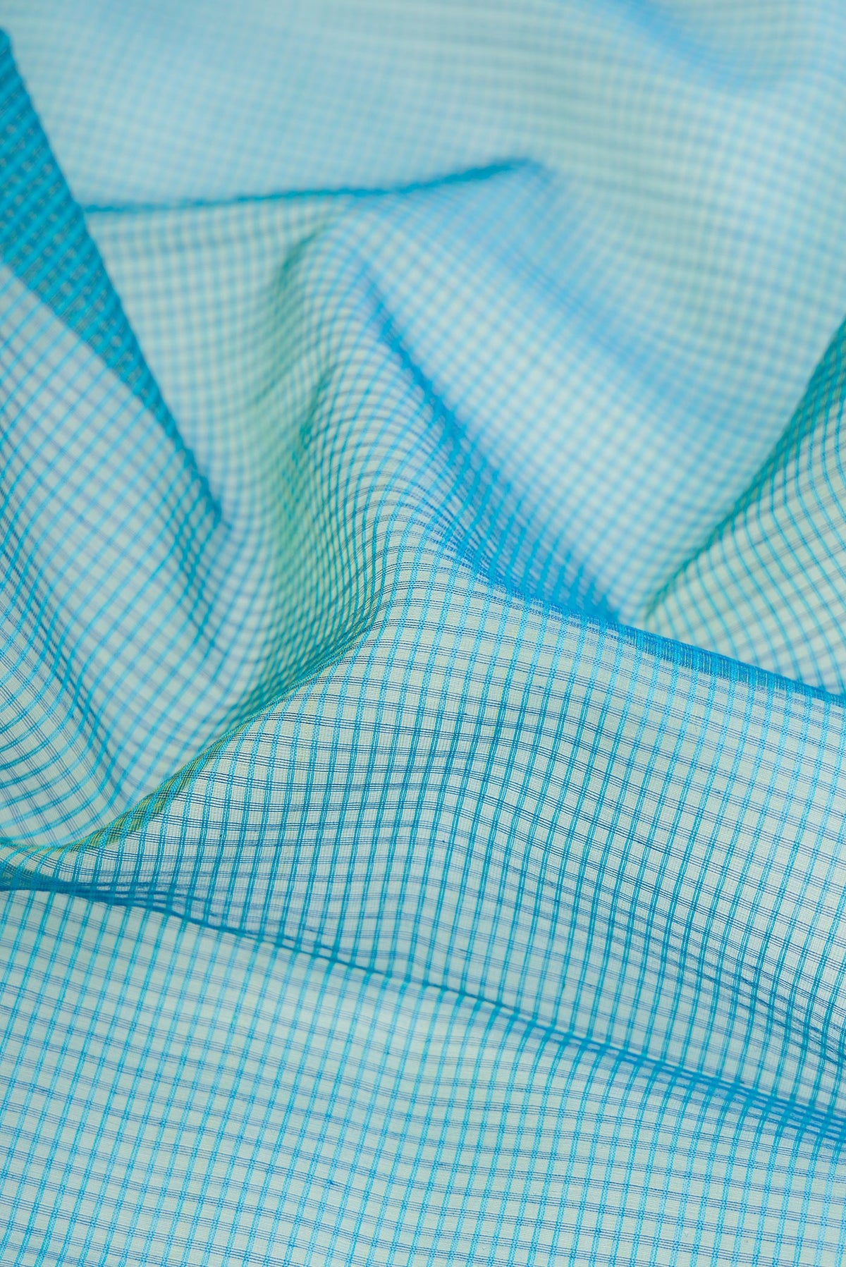 Close up of Peacock Blue Dual Tone Maheshwari Silk Cotton Saree with Checked design on the body and Zari Border.  displaying folds
