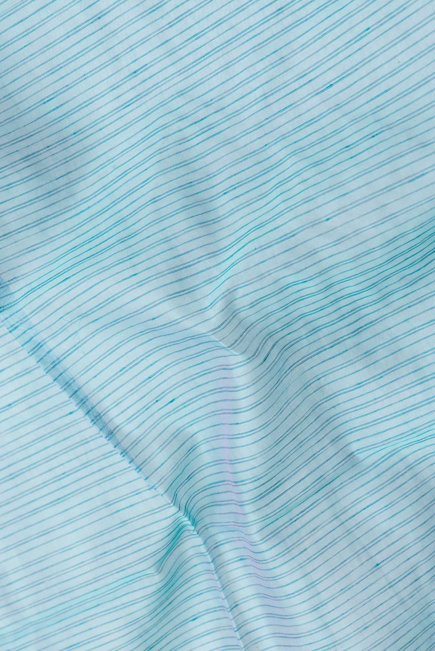 Close up of Sky Blue Dual Tone Maheshwari Silk Saree with Stripes on the body and Zari Border.  displaying folds