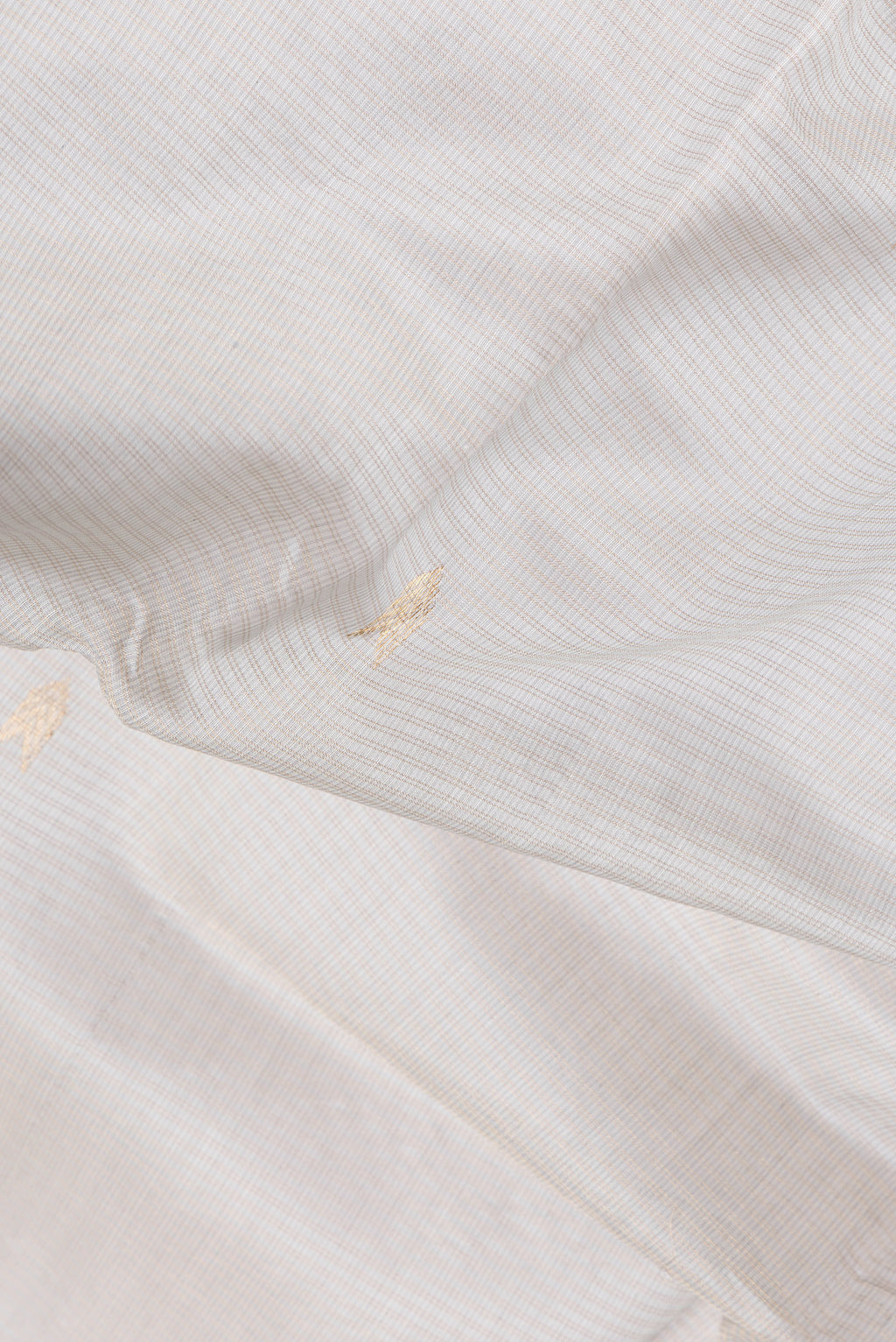 Close up of Beige Dual Tone Kota Silk Saree with Zari Butta on the body and Zari Border.  displaying folds