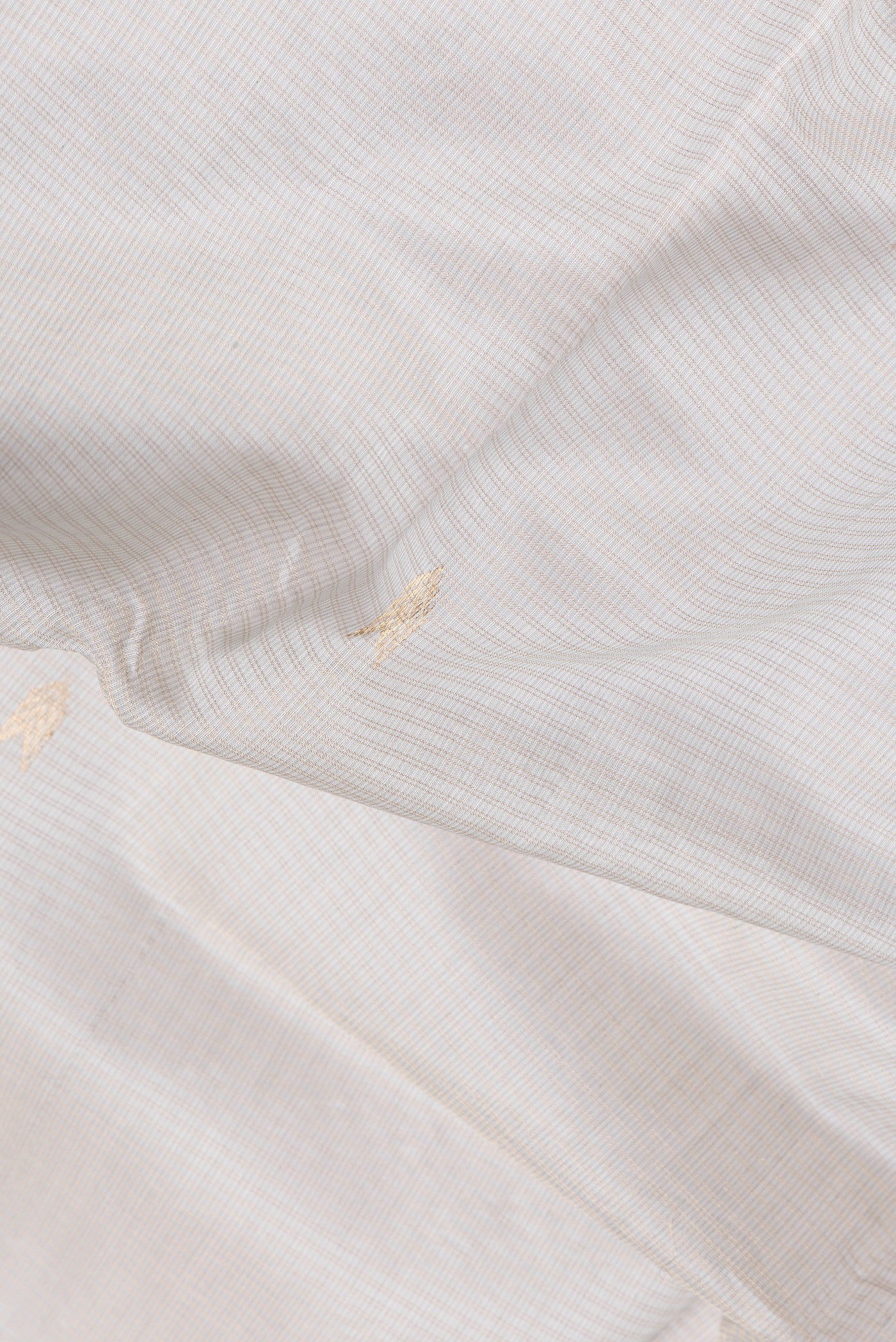 Close up of Beige Dual Tone Kota Silk Saree with Zari Butta on the body and Zari Border.  displaying folds