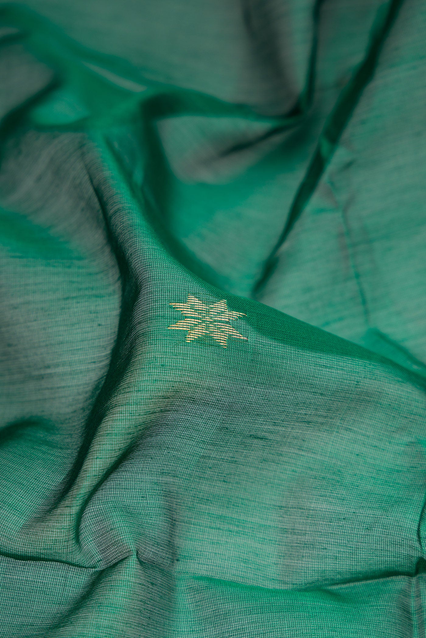 Close up of Green Dual Tone Maheshwari Silk Cotton Saree with Zari Butta on the body and Zari Border.  displaying folds