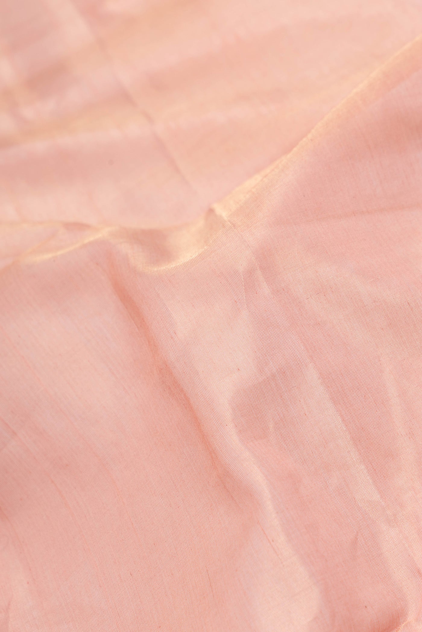 Close up of Rose Gold Dual Tone Maheshwari Silk Saree with Plain Body and Zari Border.  displaying folds