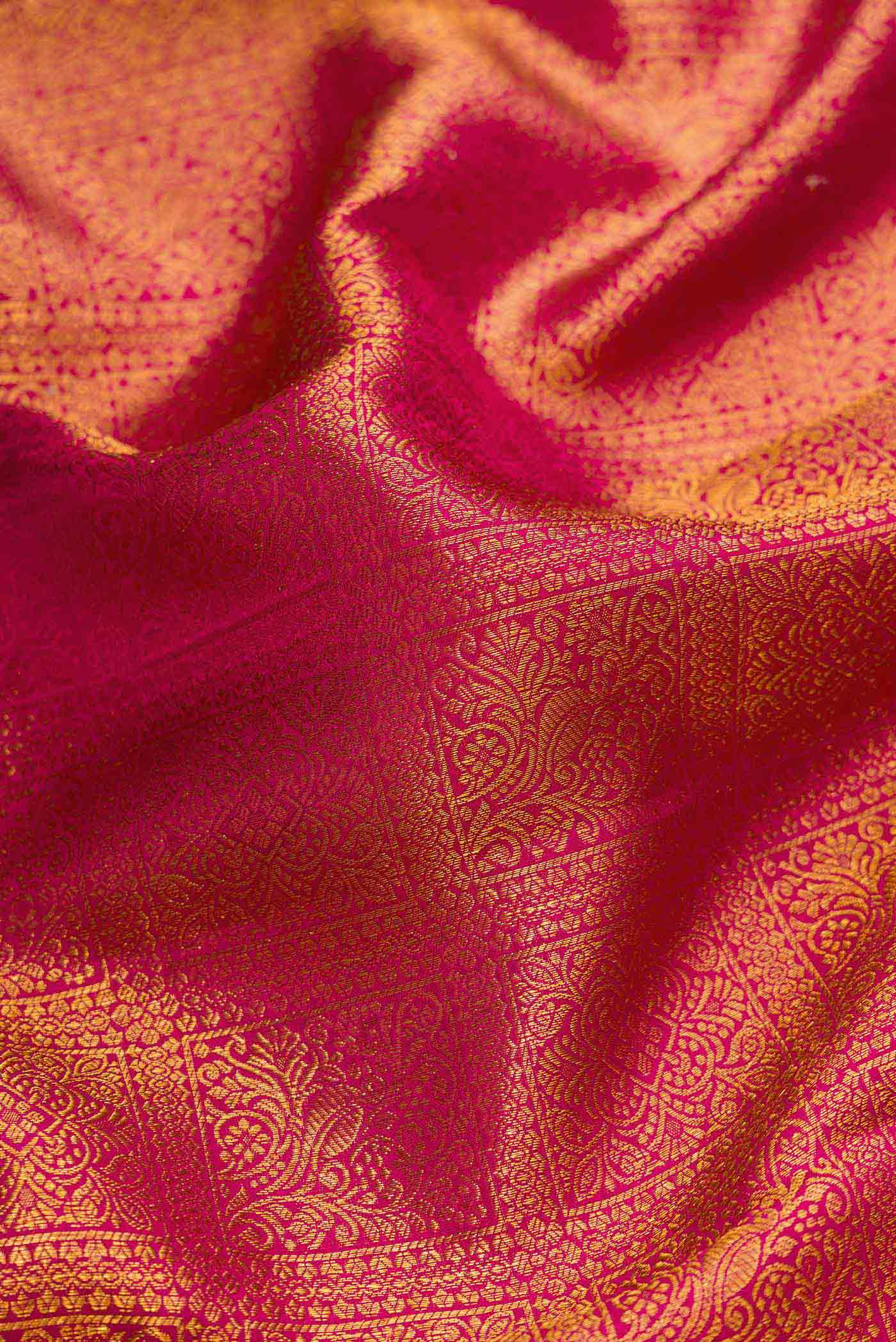 Close up of Magenta Dual Tone Kanchipuram Silk Saree with Zari Brocade on the body and Zari Border.  displaying folds