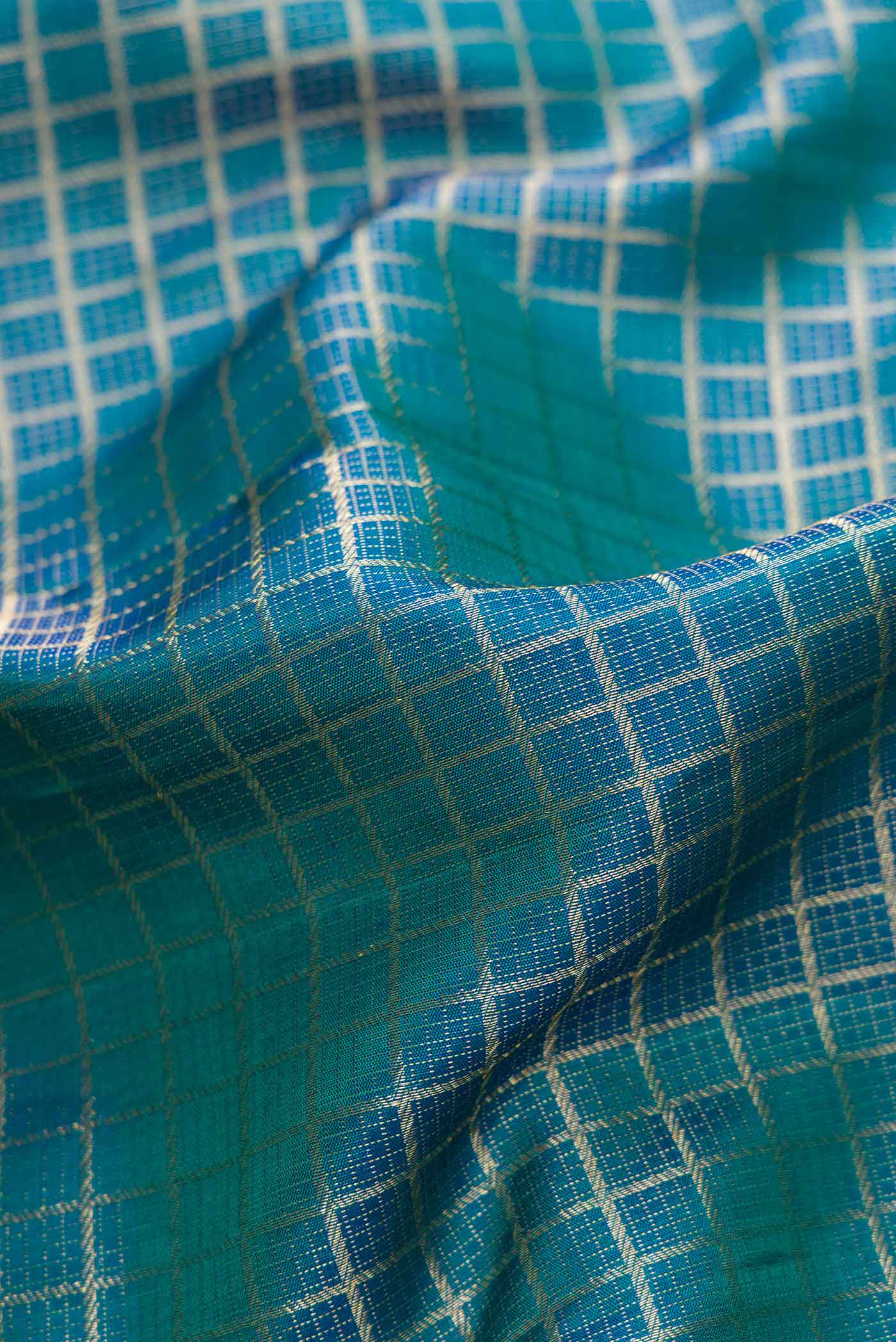 Close up of Peacock Blue Dual Tone Kanchipuram Silk Saree with Zari Brocade on the body and Zari Border.  displaying folds
