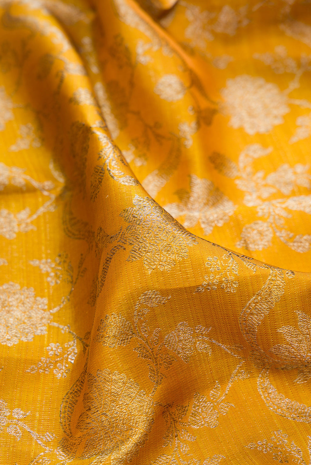 Close up of Pure Silk Mustard Kanchipuram Saree with Zari Brocade on the body and Zari Border.  displaying folds