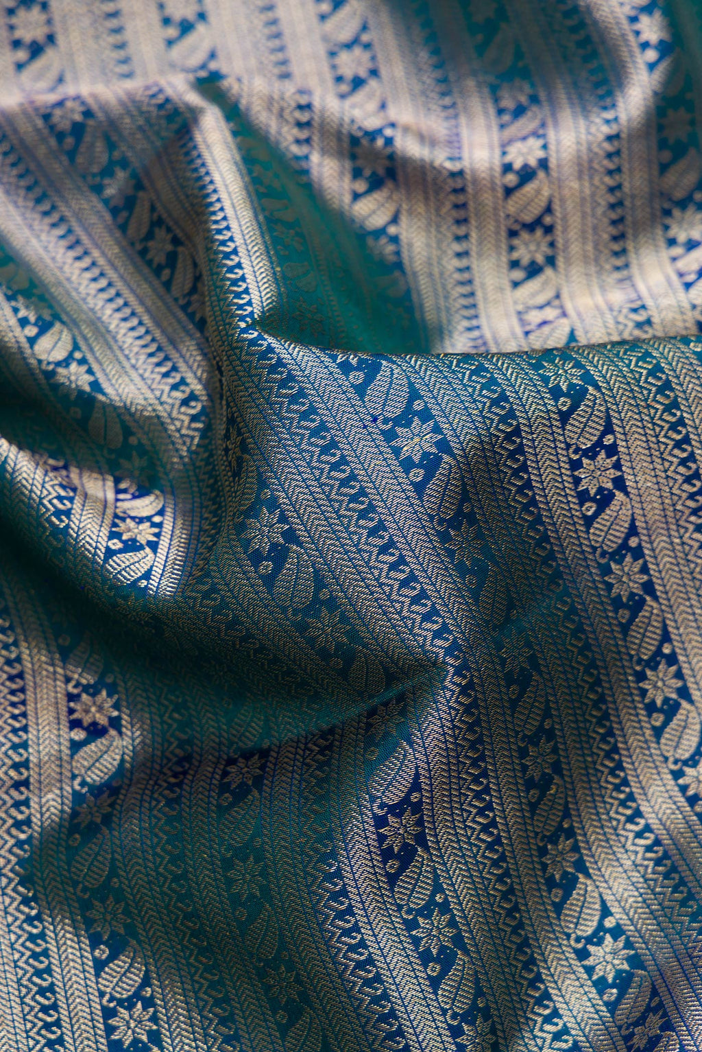 Close up of Peacock Blue Dual Tone Kanchipuram Silk Saree with Zari Brocade on the body and Zari Border.  displaying folds