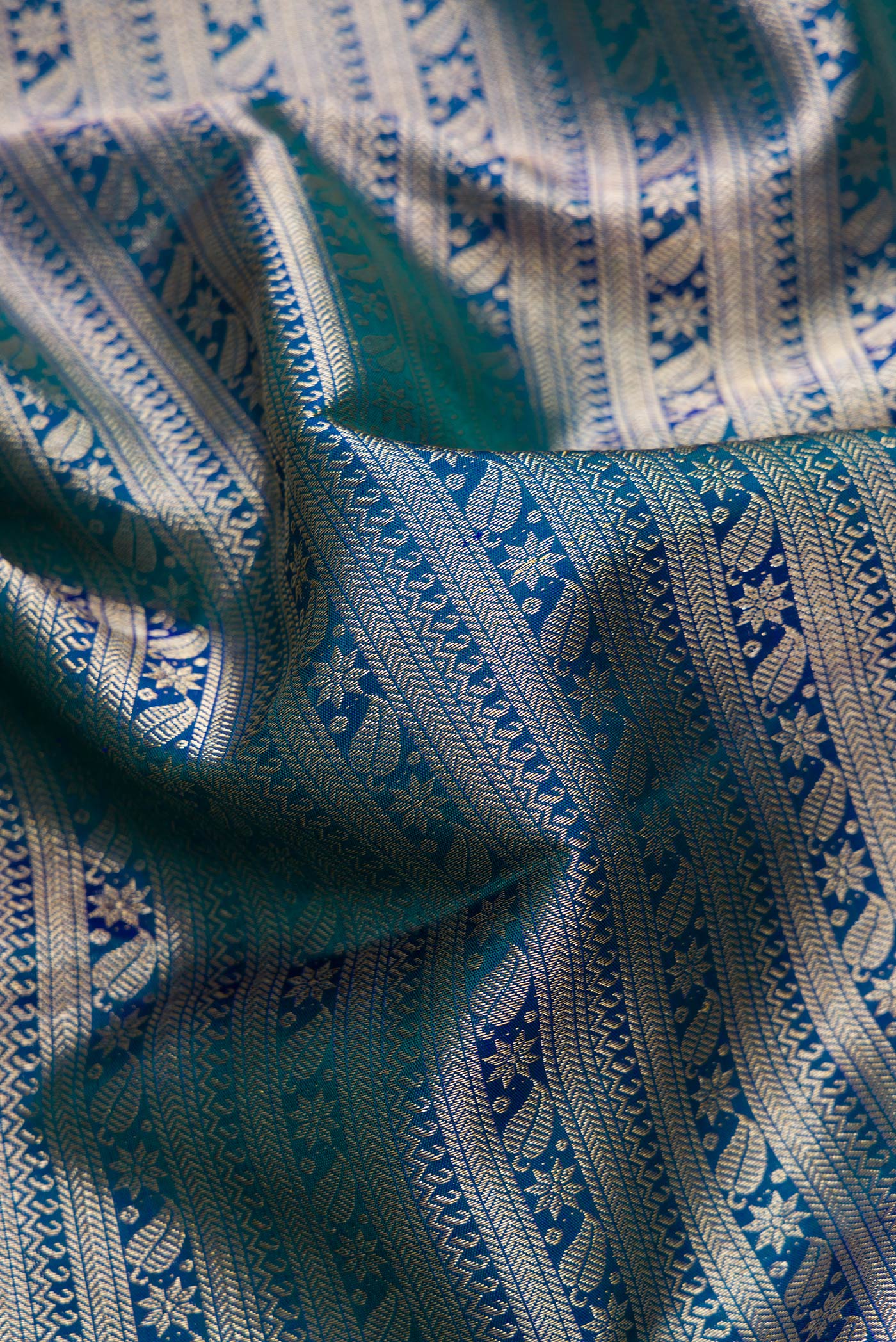 Close up of Peacock Blue Dual Tone Kanchipuram Silk Saree with Zari Brocade on the body and Zari Border.  displaying folds