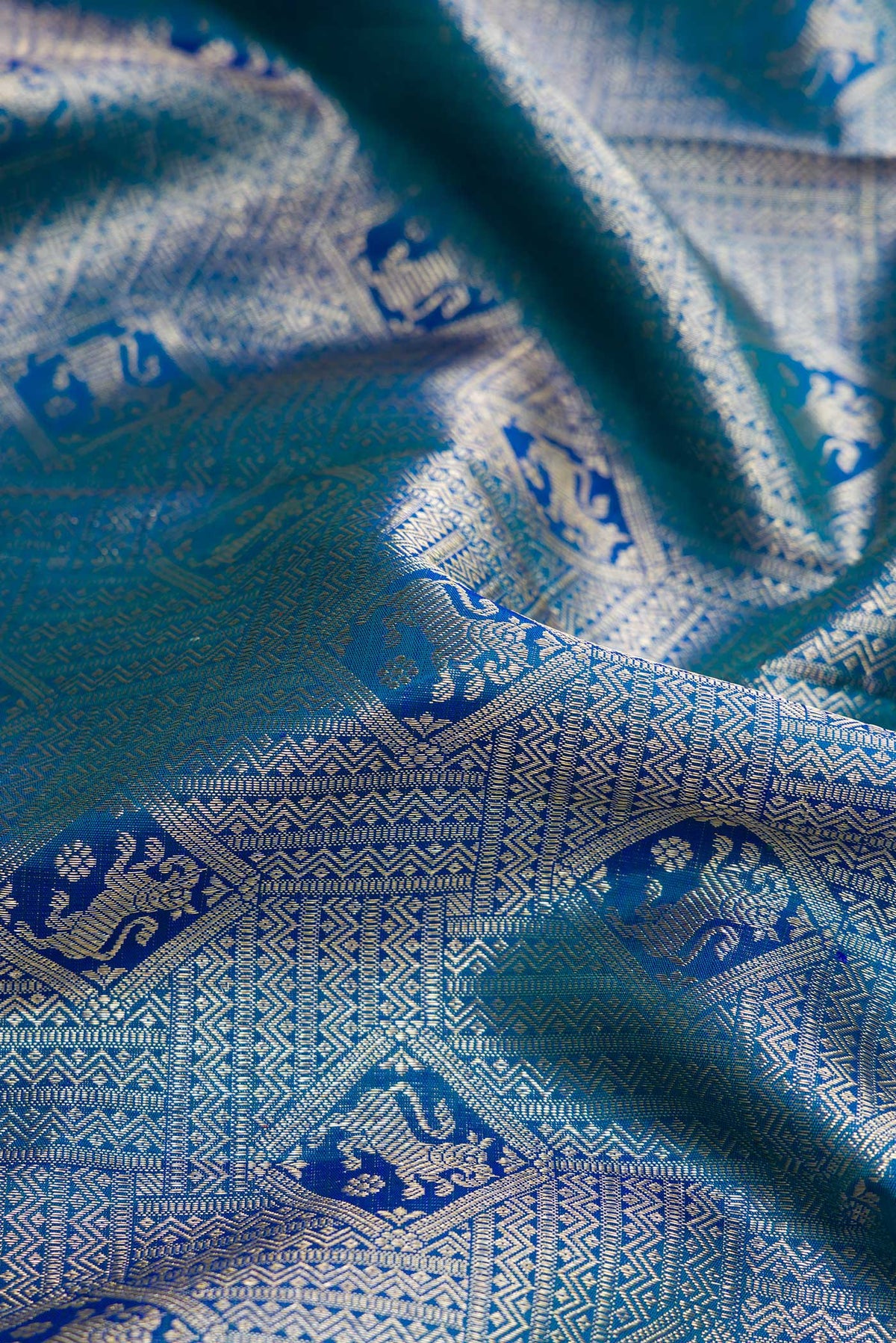 Close up of Peacock Blue Dual Tone Kanchipuram Silk Saree with Zari Brocade on the body and Zari Border.  displaying folds