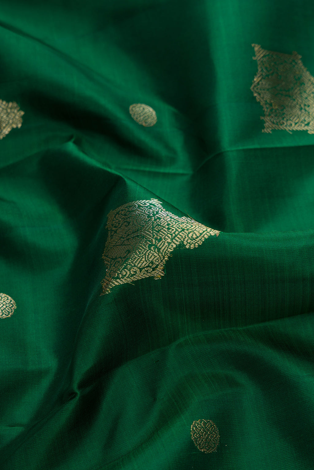 Close up of Green Dual Tone Kanjivaram Silk Saree with Zari Butta on the body and Zari Border.  displaying folds