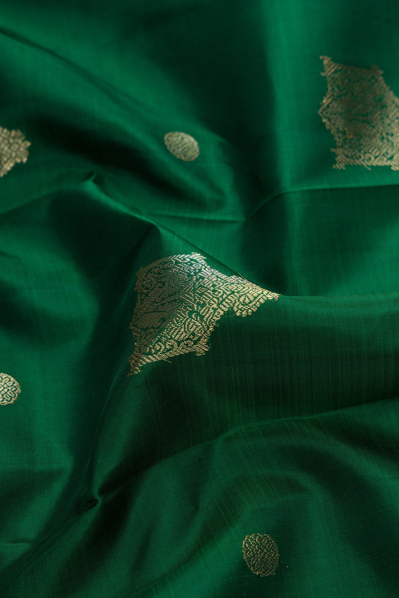 Close up of Green Dual Tone Kanjivaram Silk Saree with Zari Butta on the body and Zari Border.  displaying folds