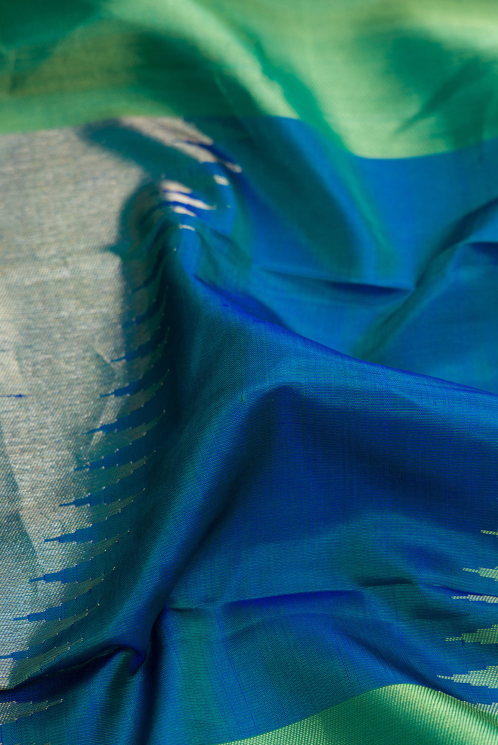 Close up of Green and Peacock Blue Color Kanchipuram Silk Saree with Zari Brocade on the body and Without Border.  displaying folds