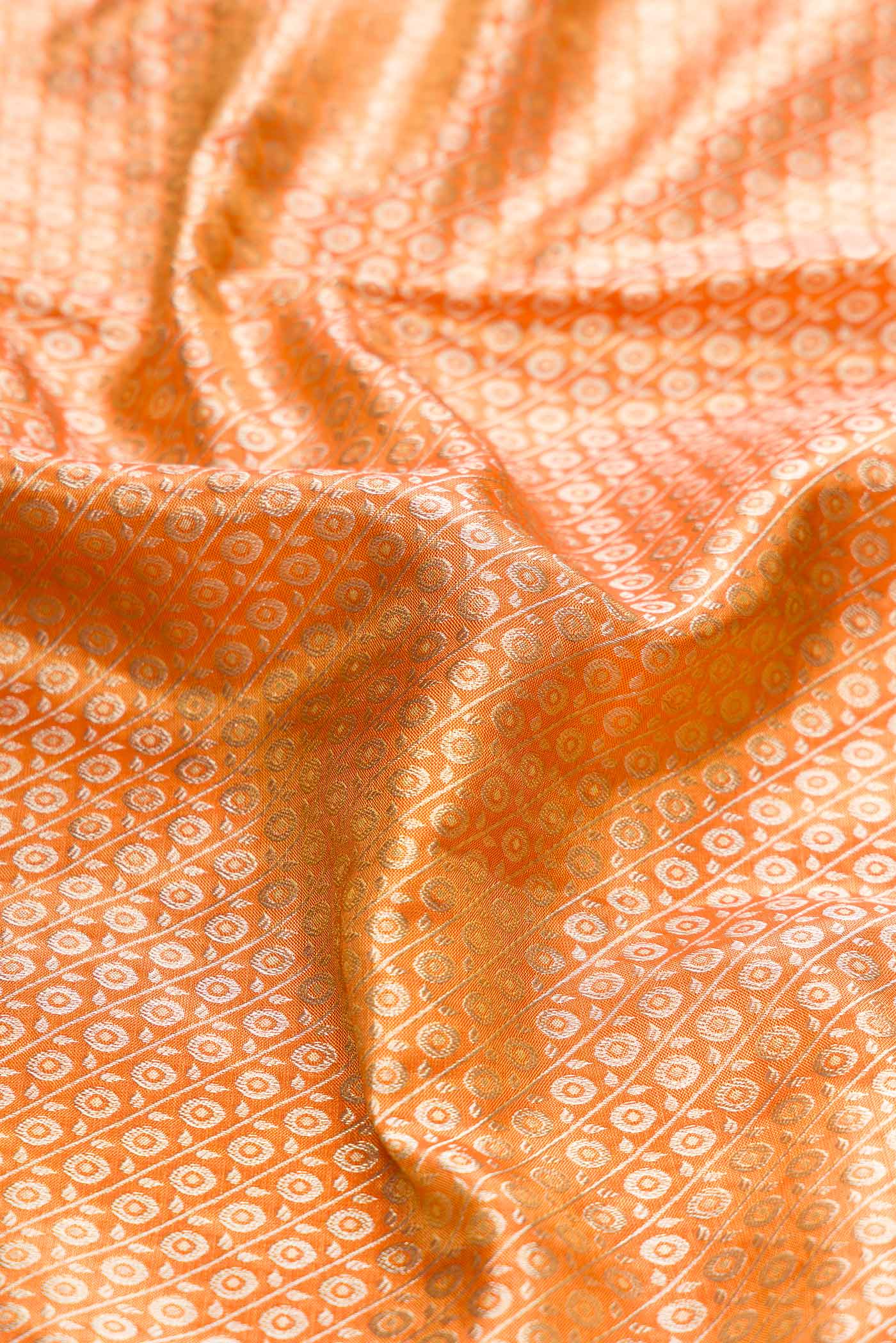 Close up of Orange Kanchipuram Tissue Silk Saree with Zari Brocade on the body and Zari Border displaying folds