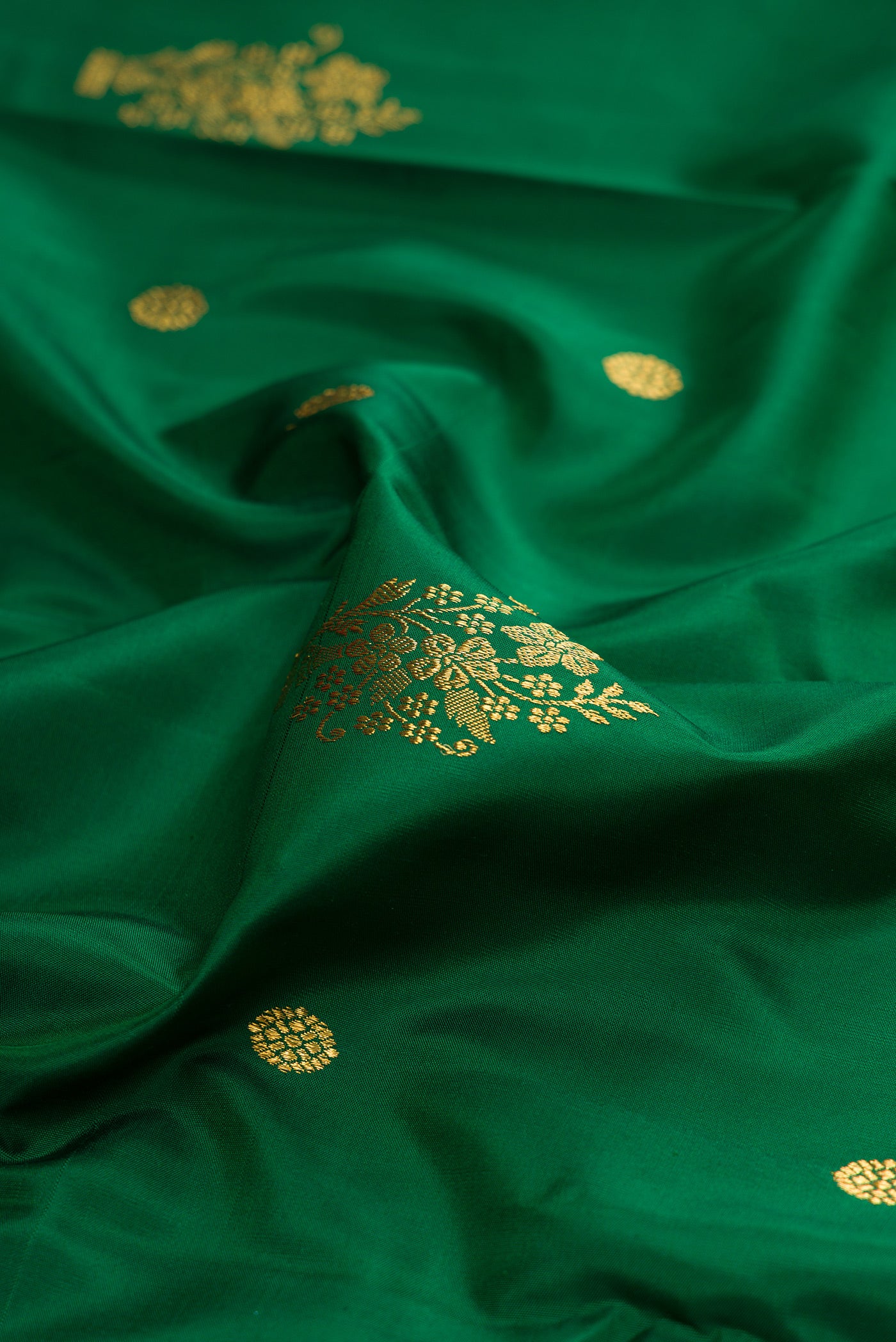 Close up of Bottle Green Kanchipuram Silk Saree with Zari Butta on the body and Fancy Border.  displaying folds