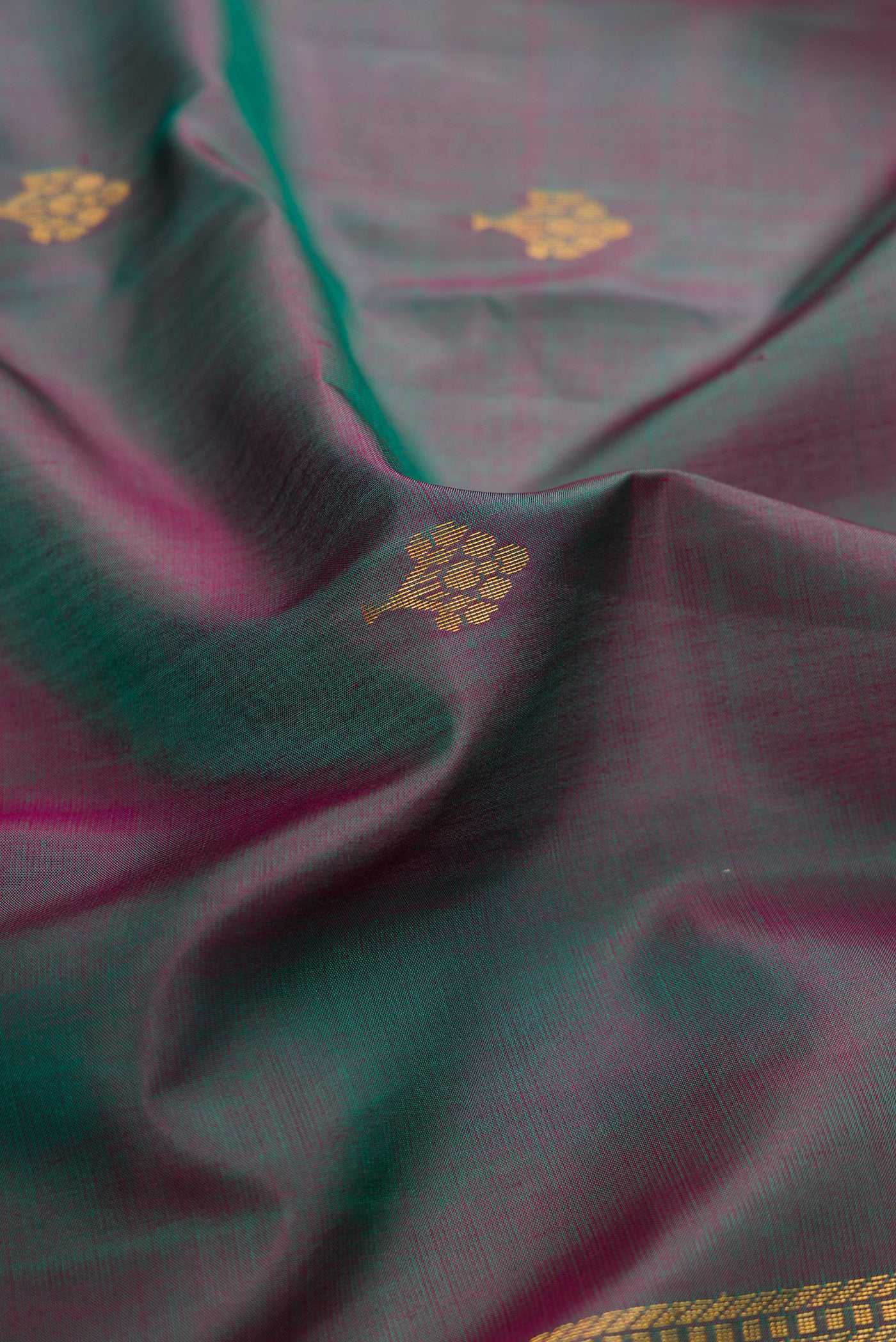 Close up of Green Dual Tone Soft Silk Saree with Zari Butta on the body and Fancy Border.  displaying folds