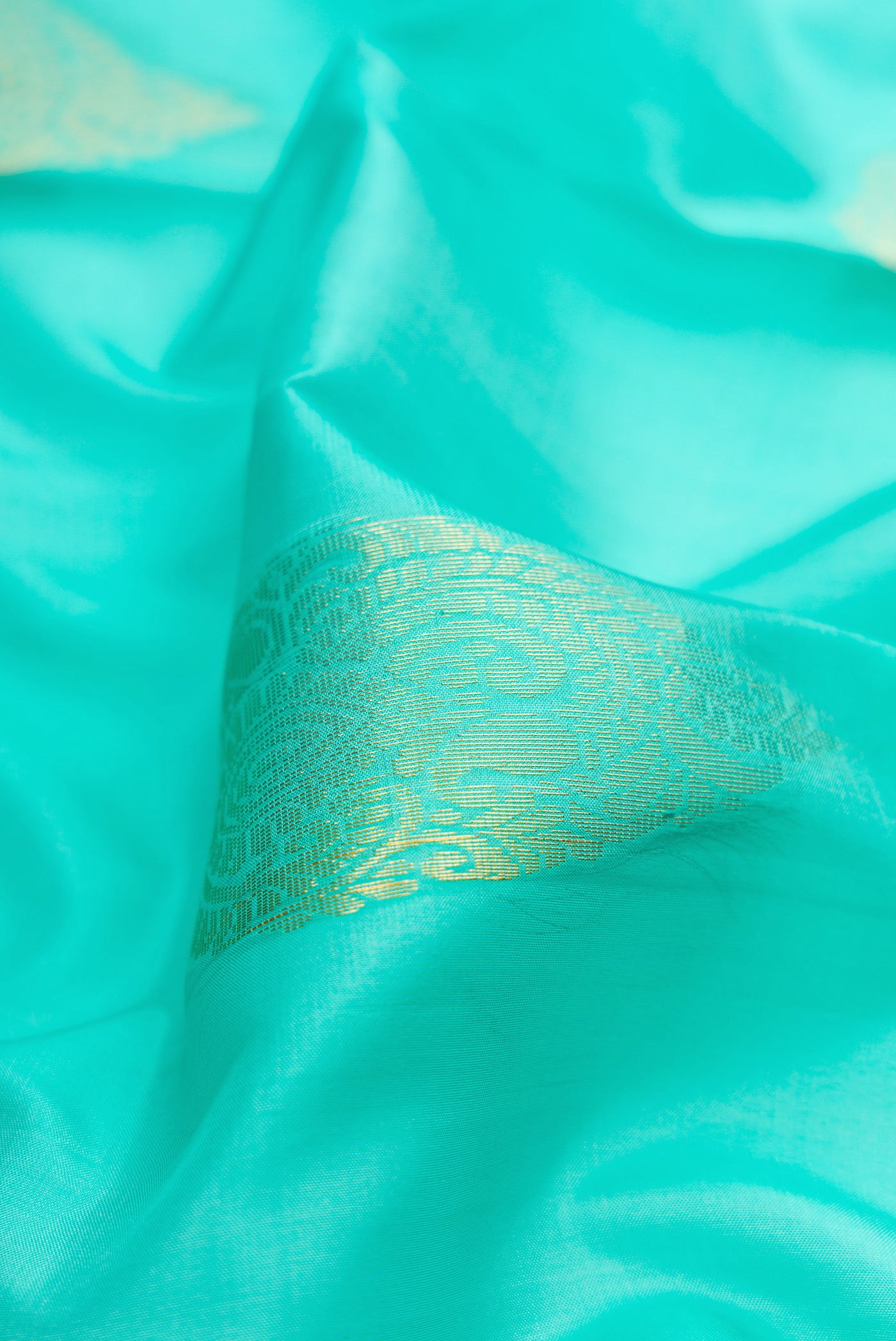 Close up of Sky Blue Soft Silk Saree with Zari Butta on the body and Zari Border.  displaying folds