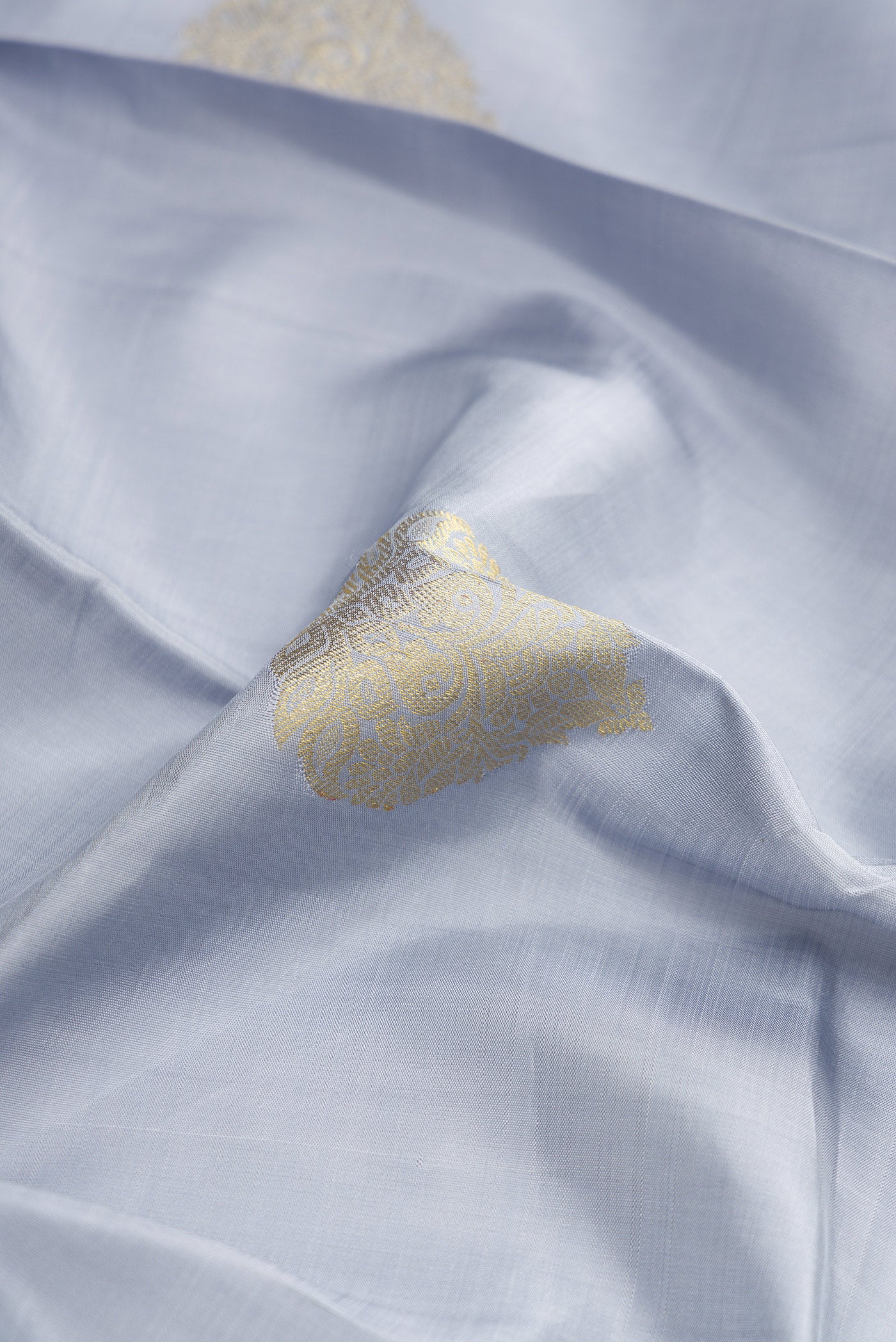 Close up of Grey Dual Tone Kanjivaram Silk Saree with Zari Butta on the body and Zari Border.  displaying folds