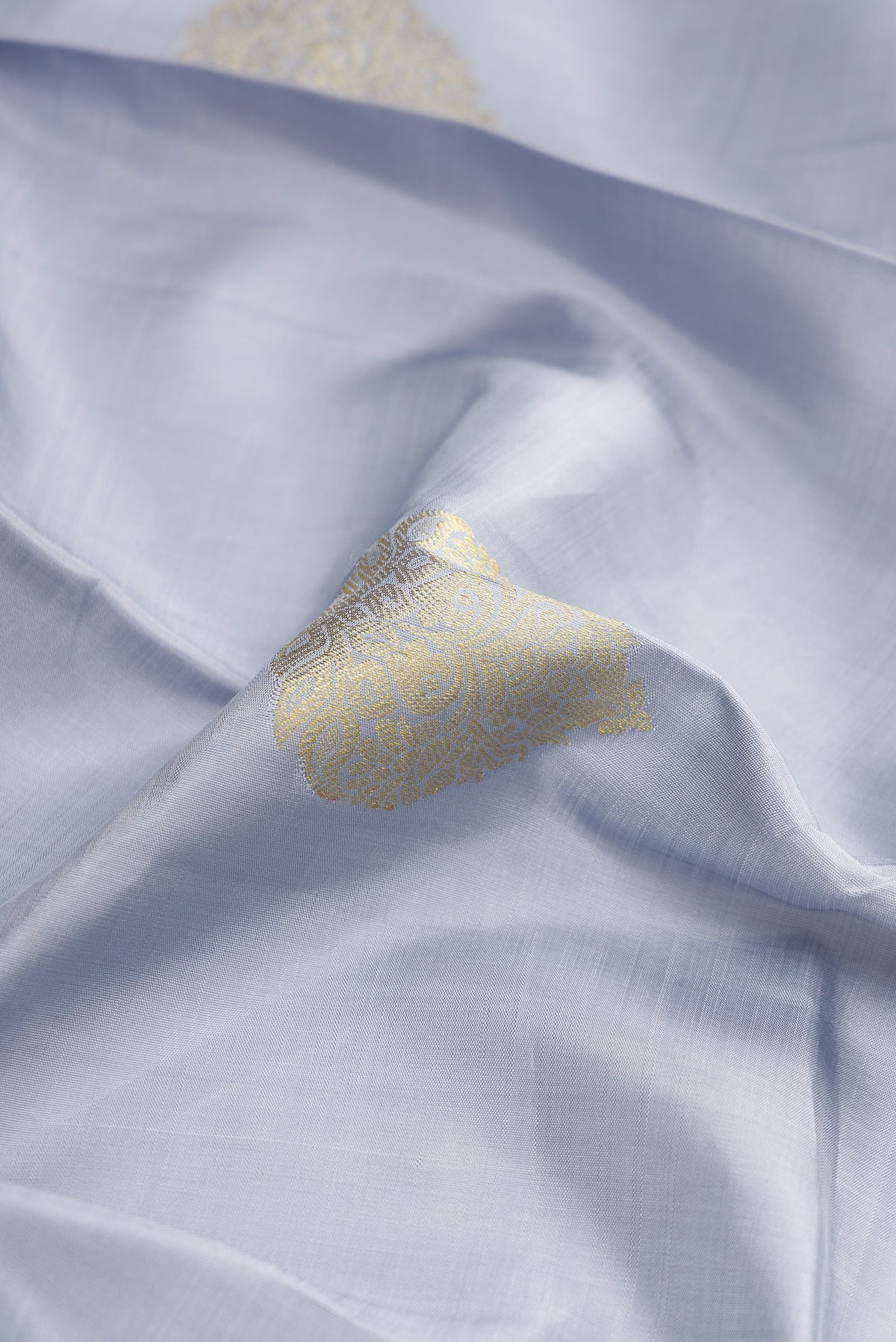 Close up of Grey Dual Tone Kanjivaram Silk Saree with Zari Butta on the body and Zari Border.  displaying folds