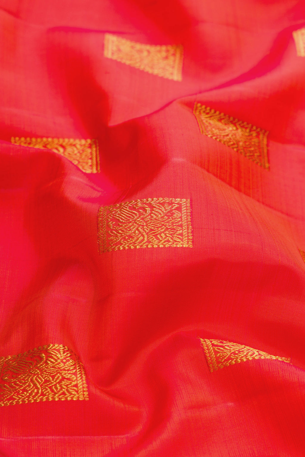 Close up of Orange Dual Tone Kanchipuram Silk Saree with Zari Butta on the body and Without Border.  displaying folds