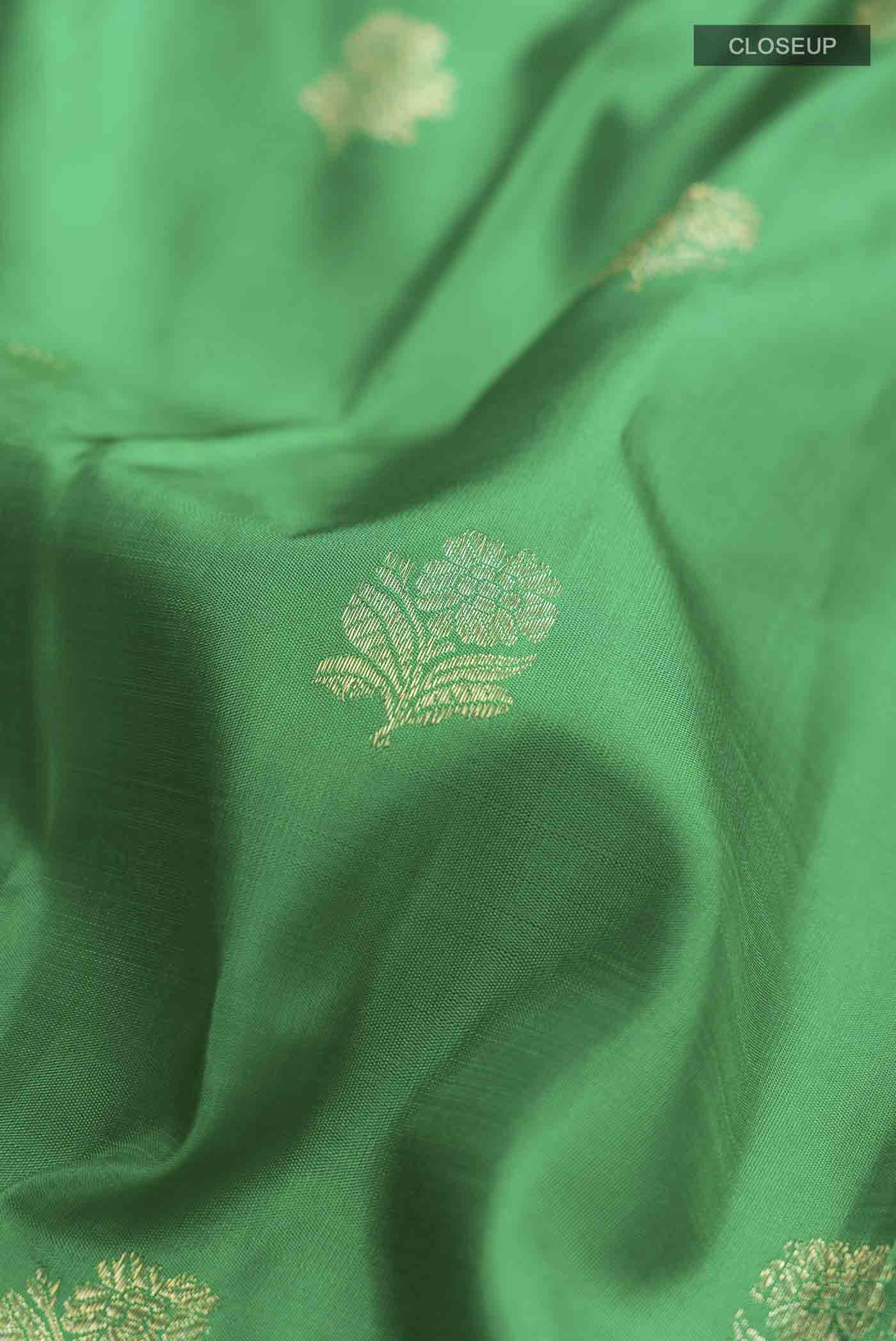 Close up of Green Kanchipuram Silk Saree with Zari Butta on the body and Zari Border displaying folds