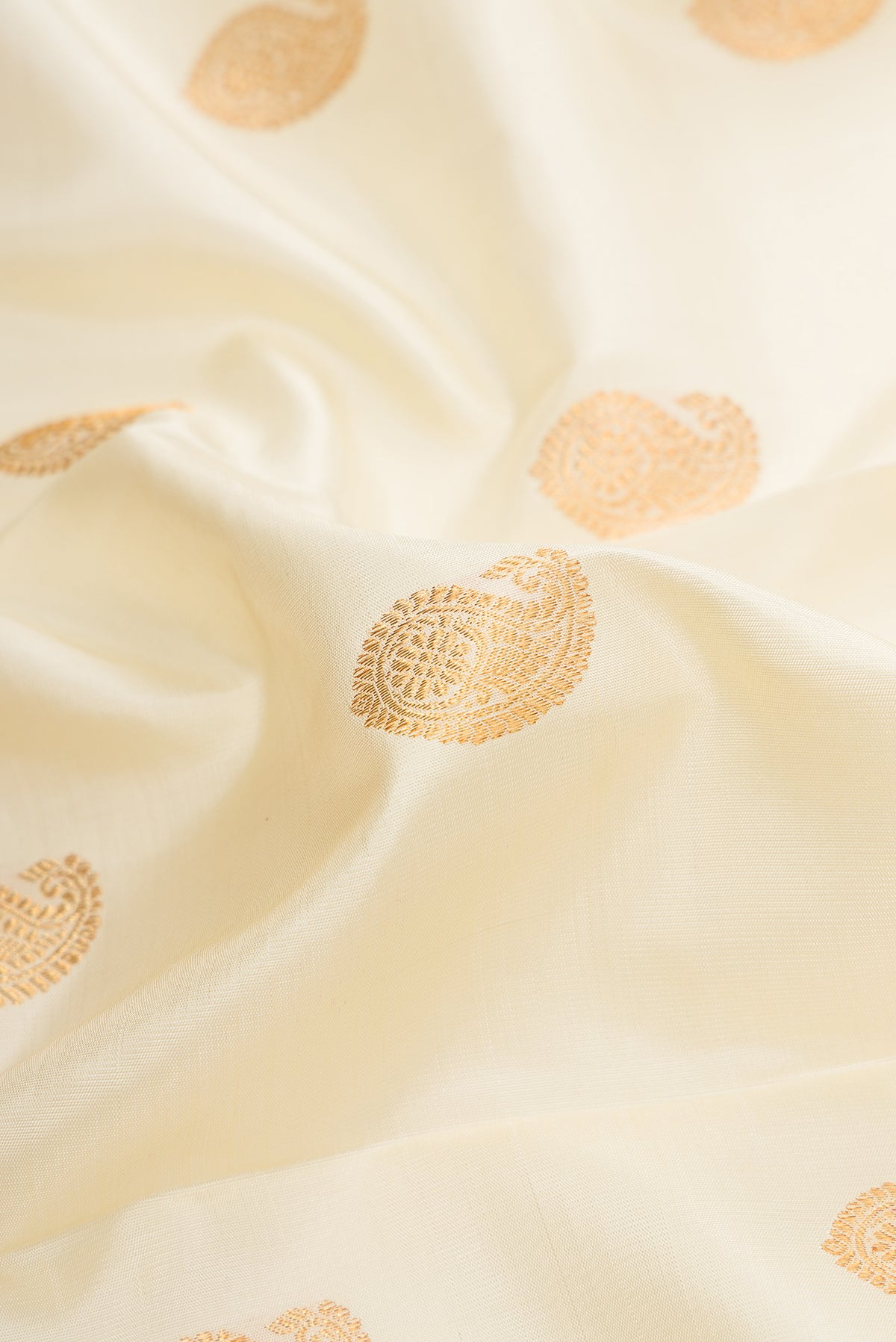 Close up of Off White Dual Tone Kanchipuram Silk Saree with Zari Butta on the body and Zari Border.  displaying folds