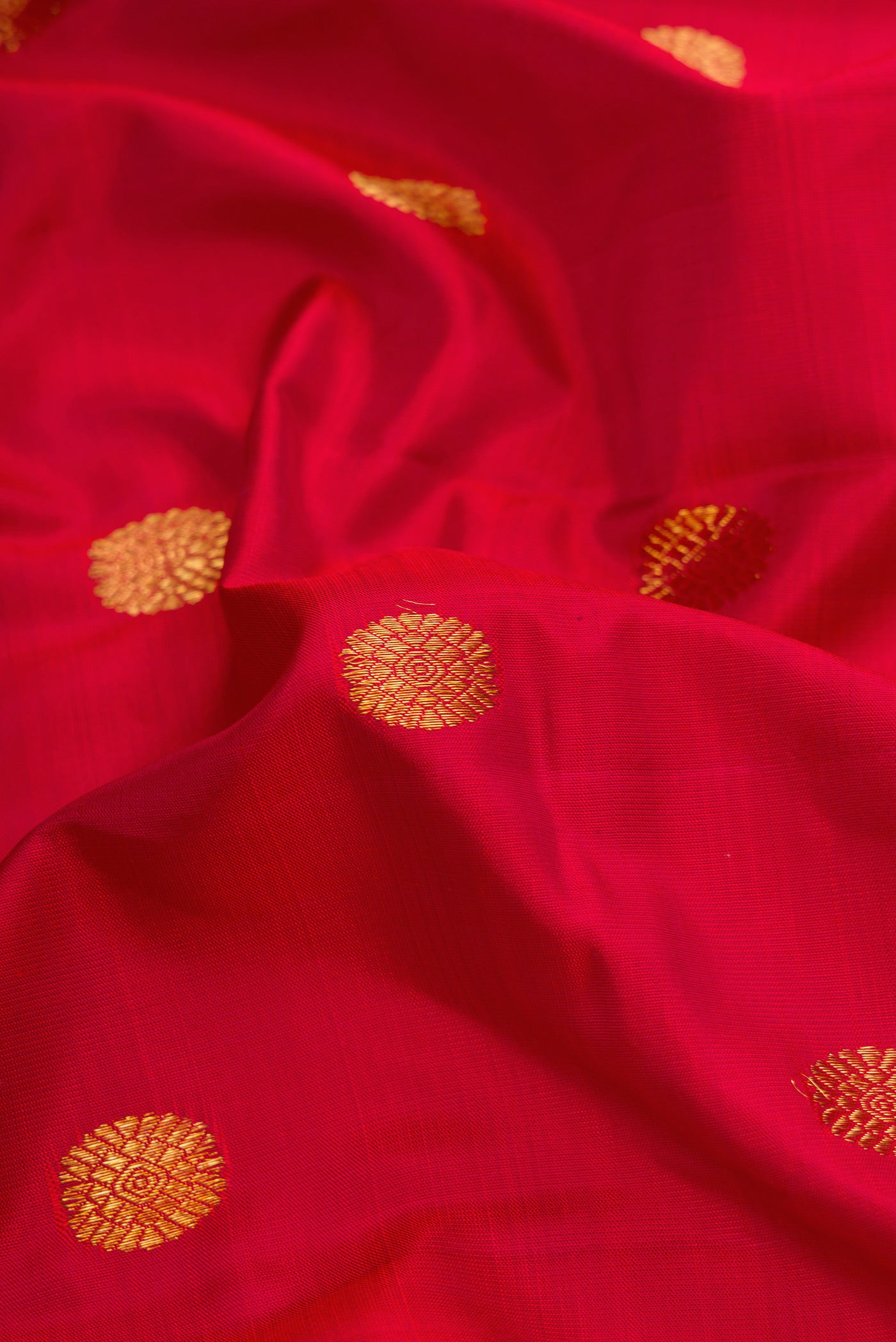 Close up of Red Dual Tone Kanchipuram Silk Saree with Zari Butta on the body and Zari Border.  displaying folds
