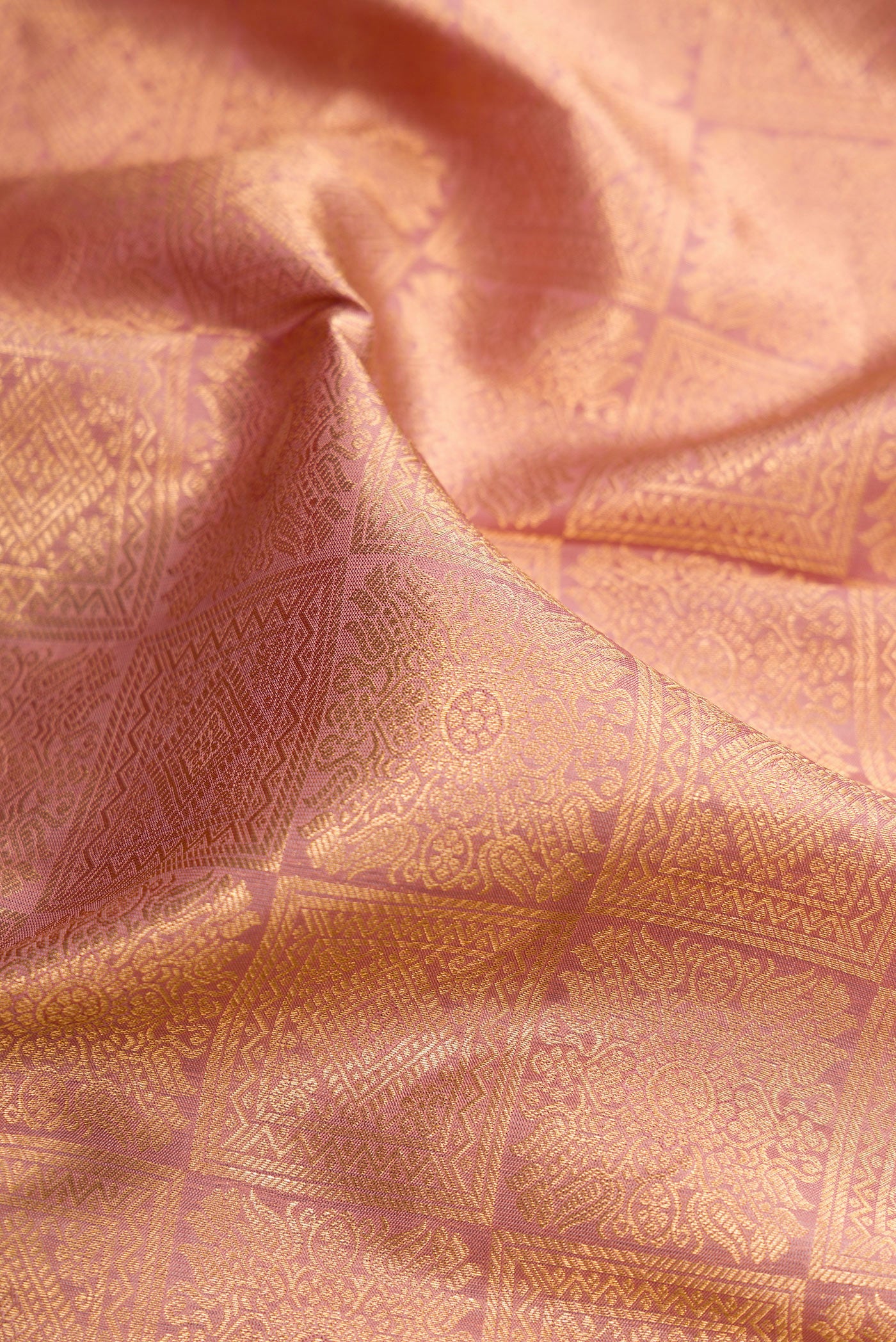 Close up of Rose Gold Kanchipuram Silk Saree with Zari Brocade on the body and Zari Border.  displaying folds