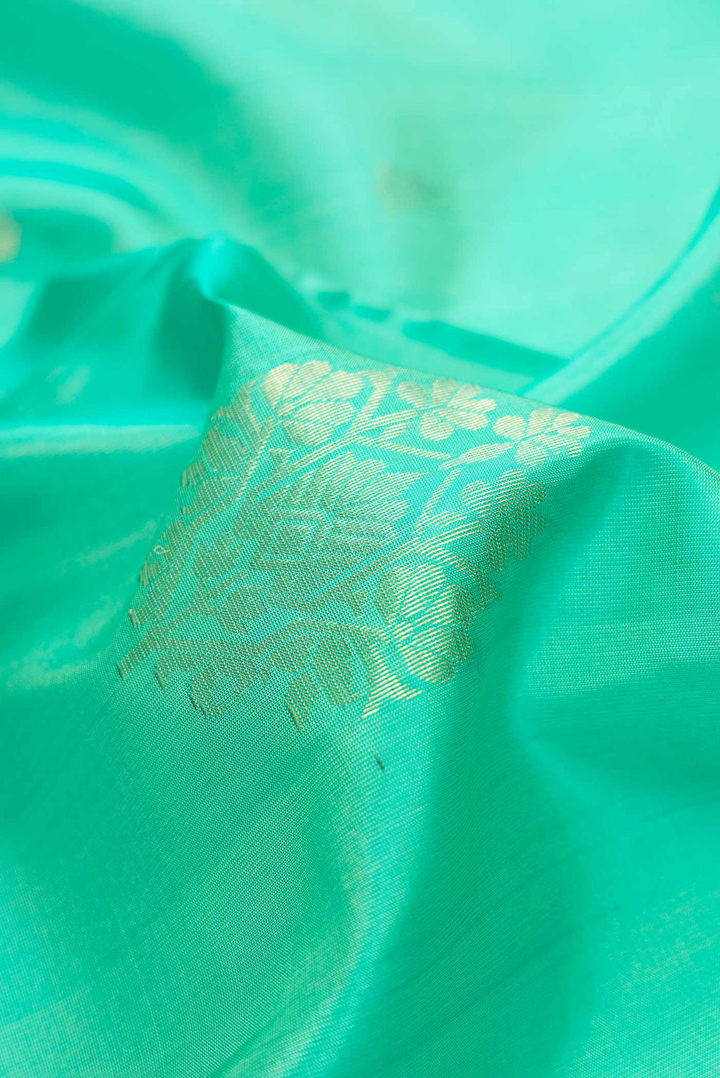 Close up of Sea Green Dual Tone Soft Silk Saree with Zari Butta on the body and Zari Border.  displaying folds