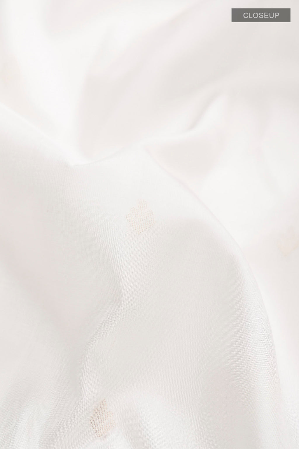 Close up of White Soft Silk Saree with Zari Butta on the body and Zari Border displaying folds
