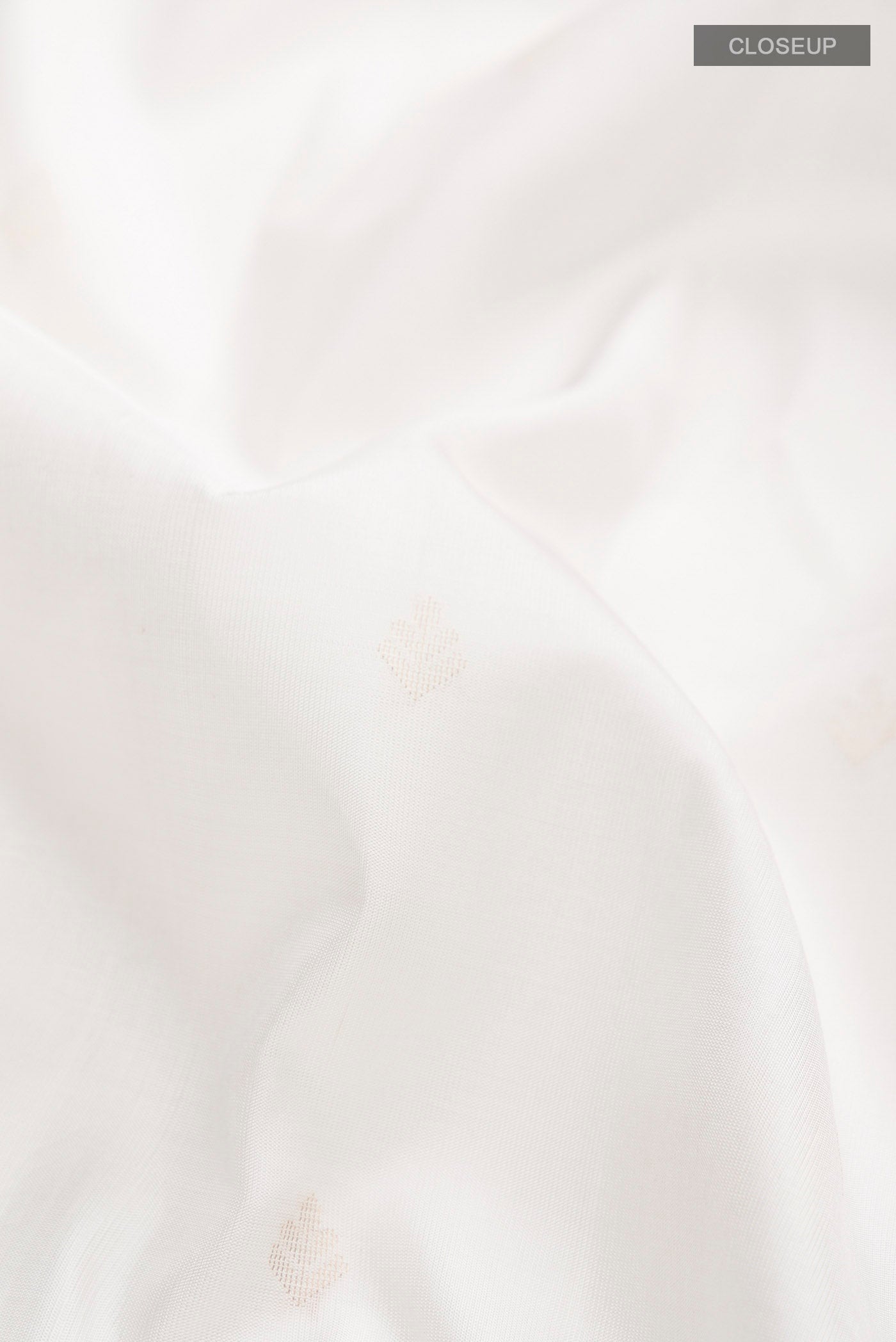 Close up of White Soft Silk Saree with Zari Butta on the body and Zari Border displaying folds