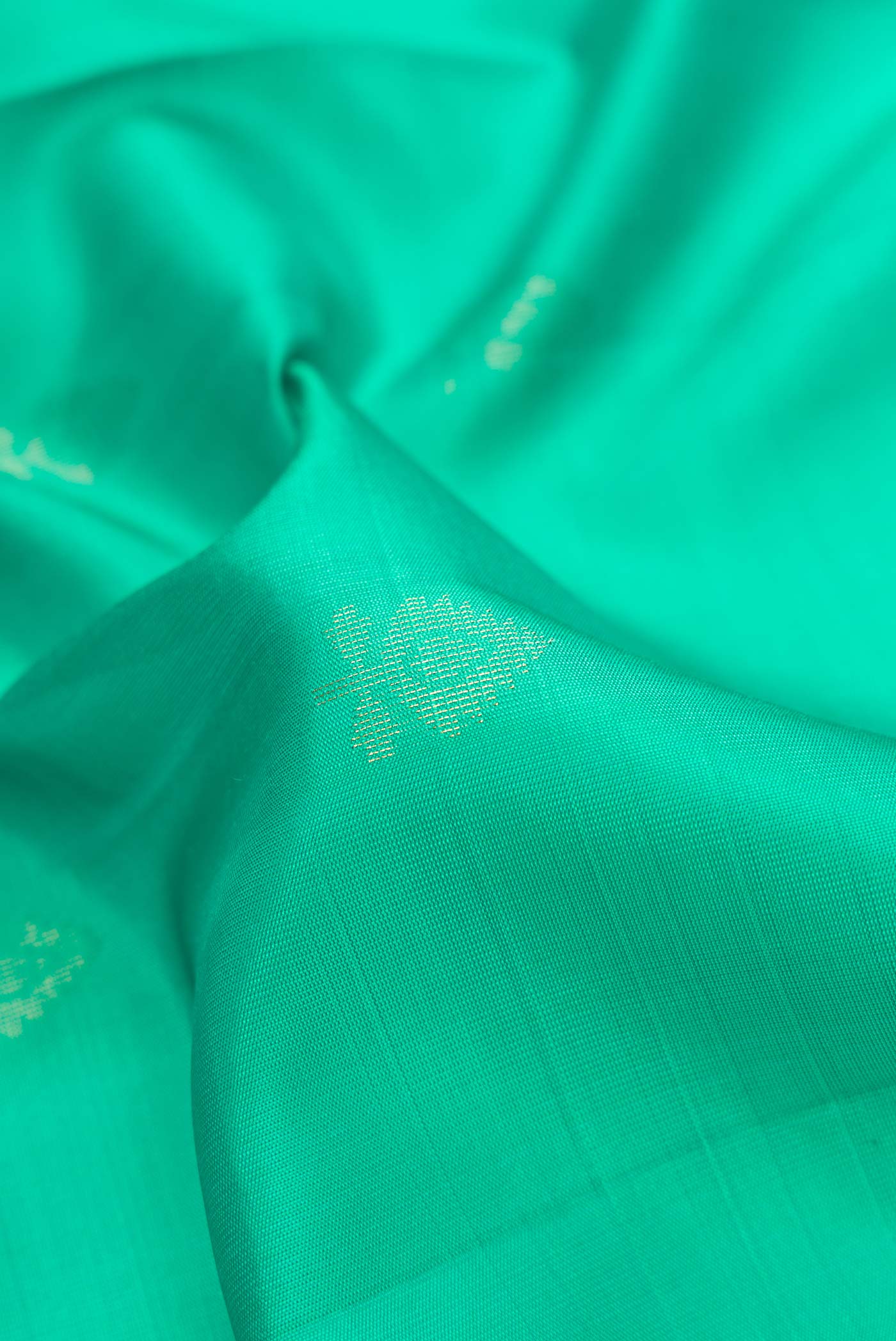 Close up of Green Dual Tone Soft Silk Saree with Zari Butta on the body and Zari Border.  displaying folds