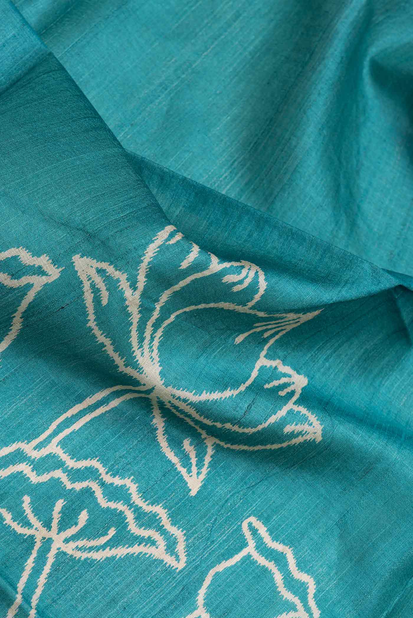 Close up of Sky Blue Dual Tone Tussar Silk Saree with Printed design on the body and Zari Border.  displaying folds