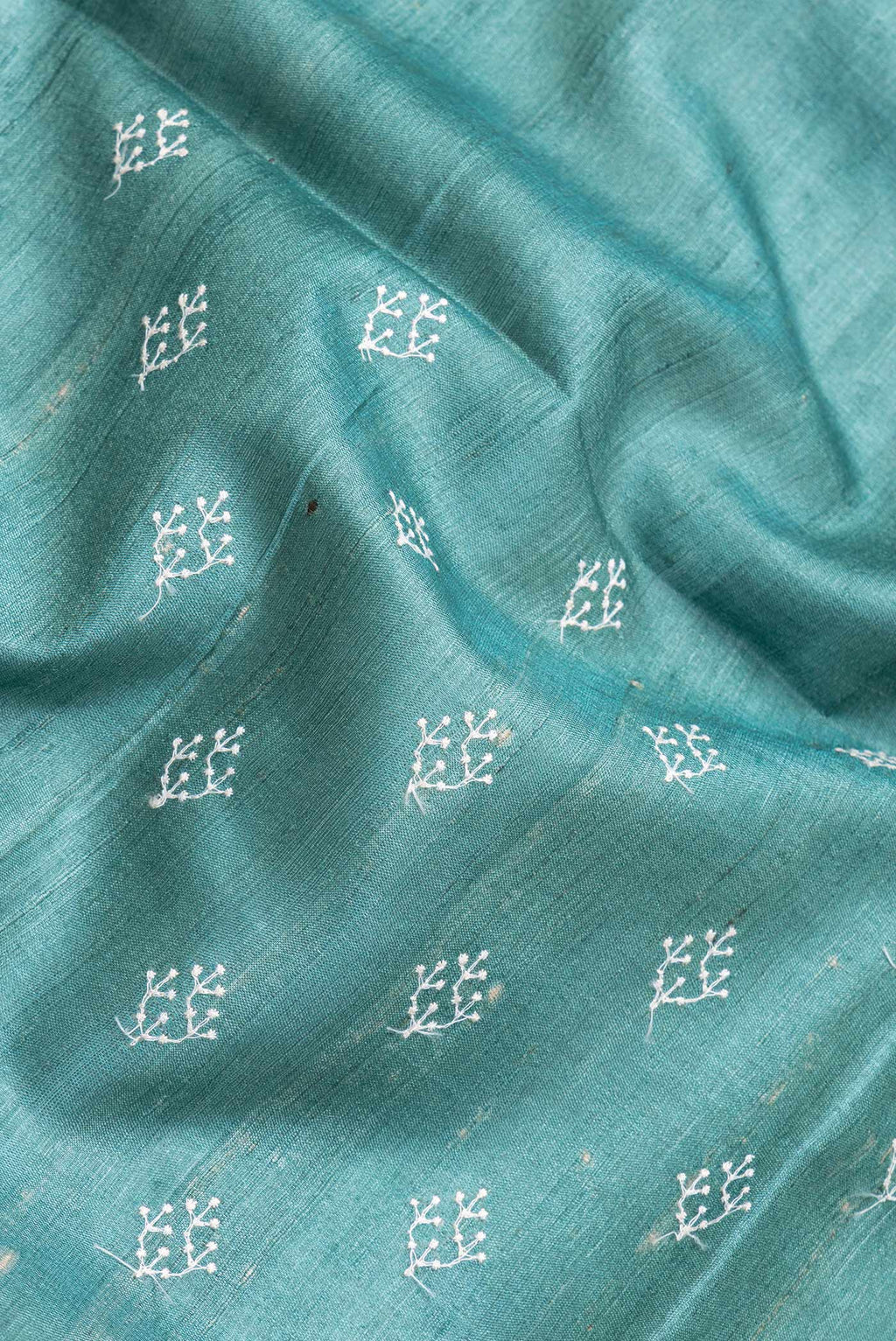 Close up of Green Dual Tone Tussar Silk Saree with Embroidery on the body and Zari Border.  displaying folds