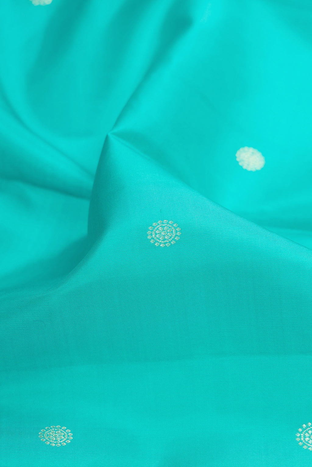 Close up of Turquoise Kanchipuram Silk Saree with Zari Butta on the body and Zari Border.  displaying folds