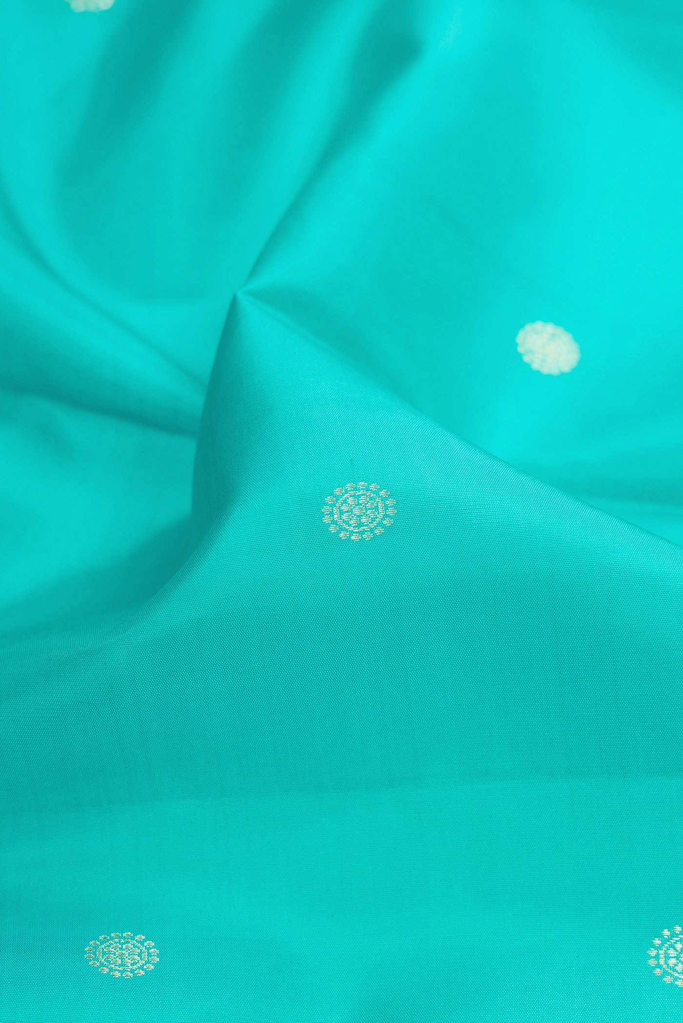Close up of Turquoise Kanchipuram Silk Saree with Zari Butta on the body and Zari Border.  displaying folds