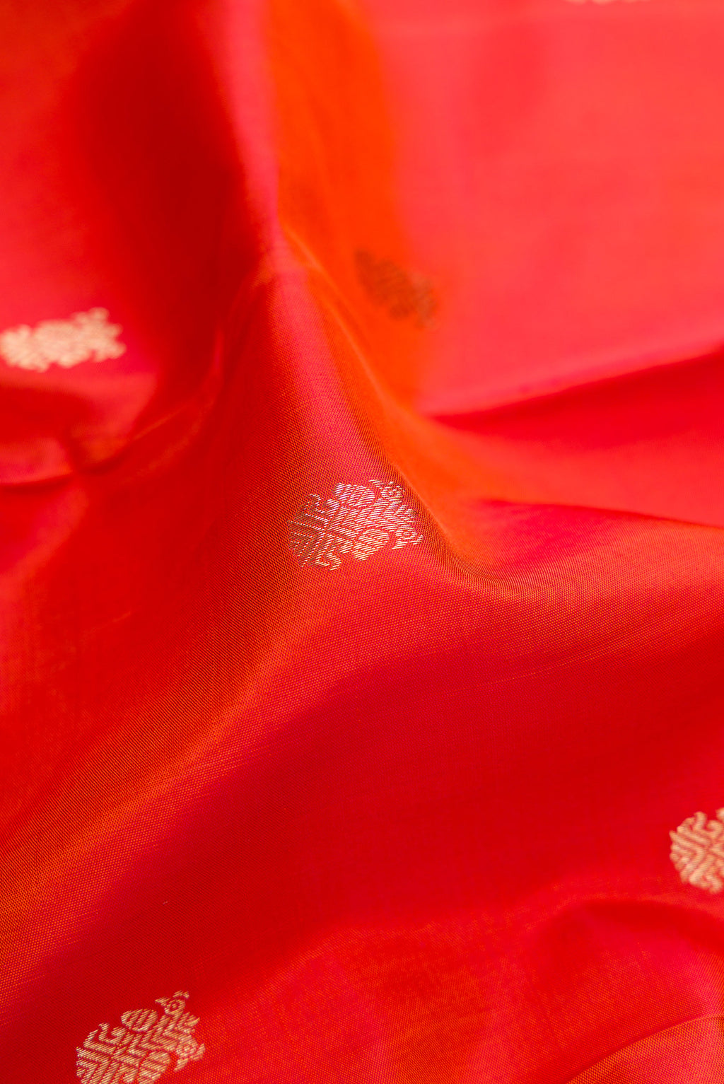 Close up of Orange Dual Tone Kanchipuram Silk Saree with Zari Butta on the body and Zari Border.  displaying folds