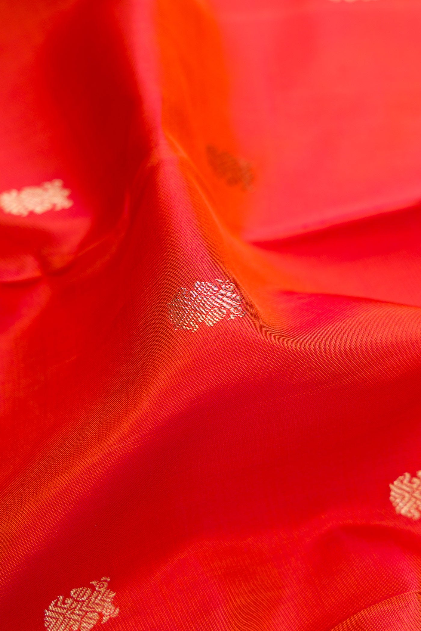Close up of Orange Dual Tone Kanchipuram Silk Saree with Zari Butta on the body and Zari Border.  displaying folds