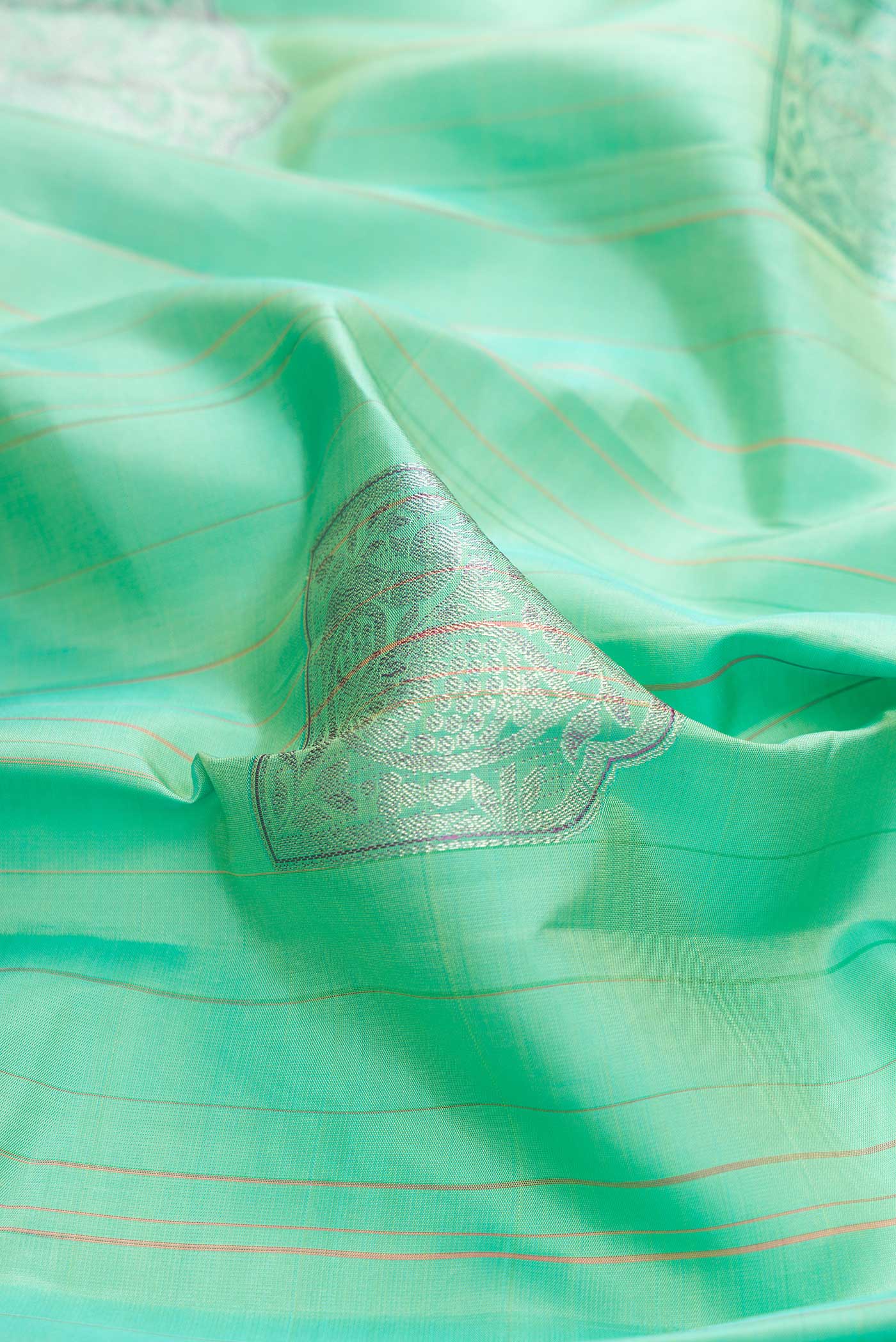 Close up of Sea Green Dual Tone Kanchipuram Silk Saree with Zari Butta on the body and Without Border displaying folds