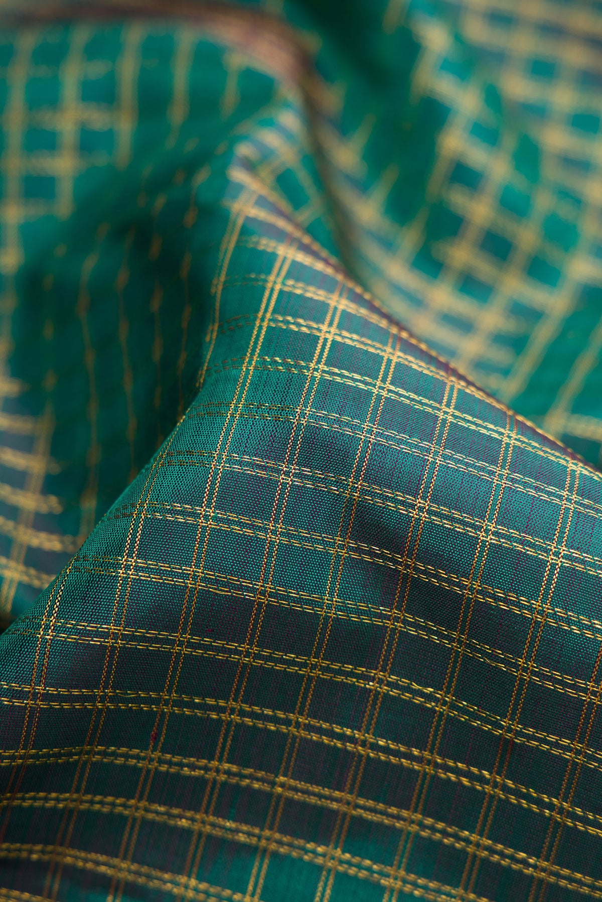 Close up of Green Dual Tone Kanjivaram Silk Saree with Checked design on the body and Zari Border.  displaying folds