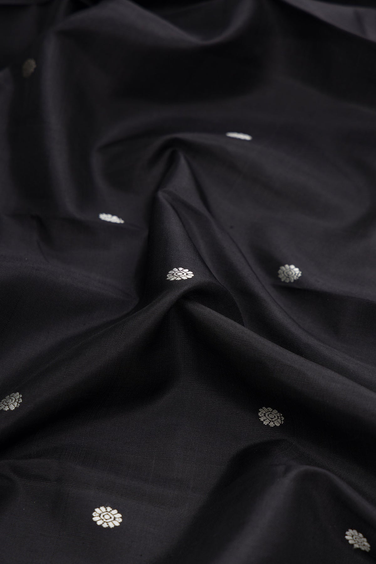 Close up of Black Dual Tone Kanchipuram Silk Saree with Thread Butta on the body and Zari Border displaying folds