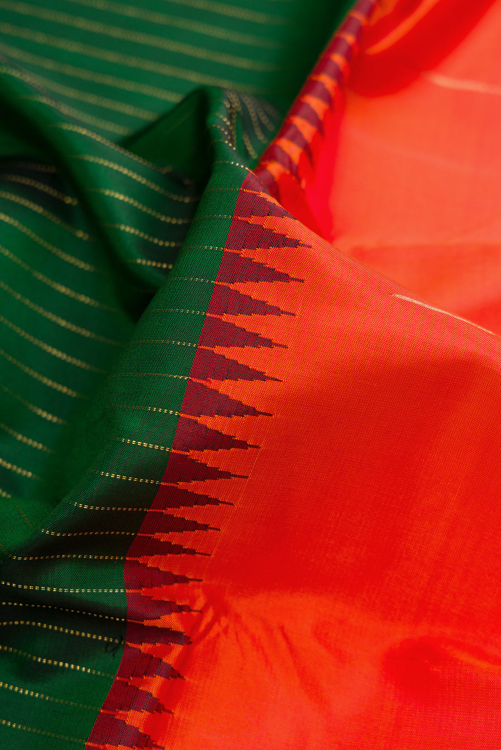Close up of Orange Dual Tone Kanjivaram Silk Saree with Zari Butta on the body and Zari Border.  displaying folds