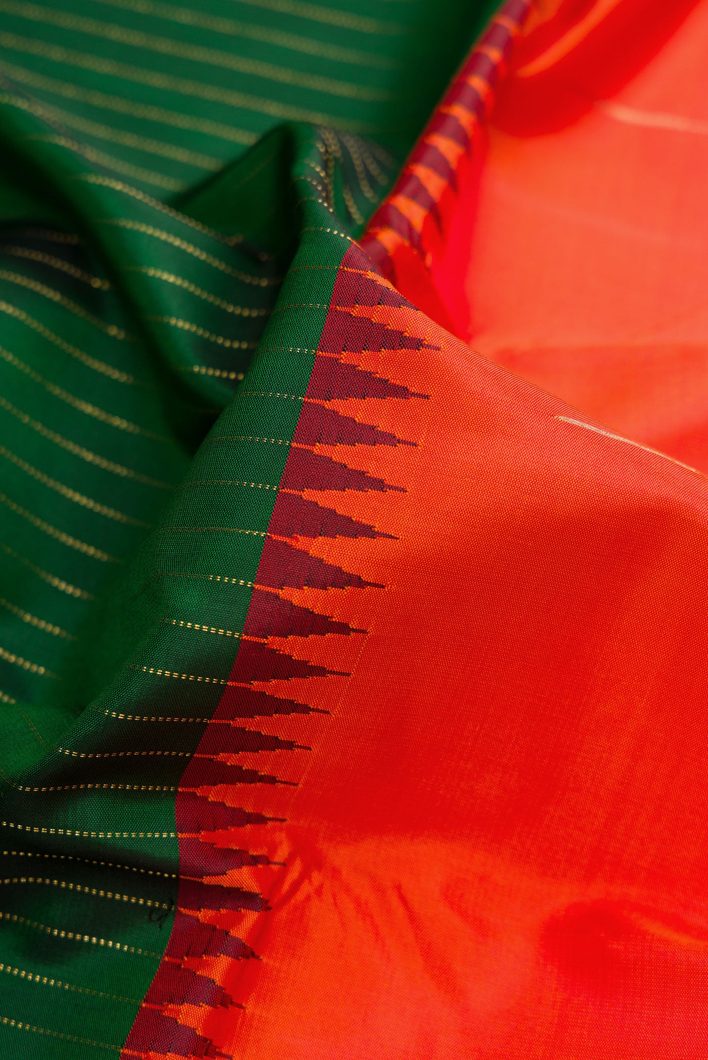Close up of Orange Dual Tone Kanjivaram Silk Saree with Zari Butta on the body and Zari Border.  displaying folds