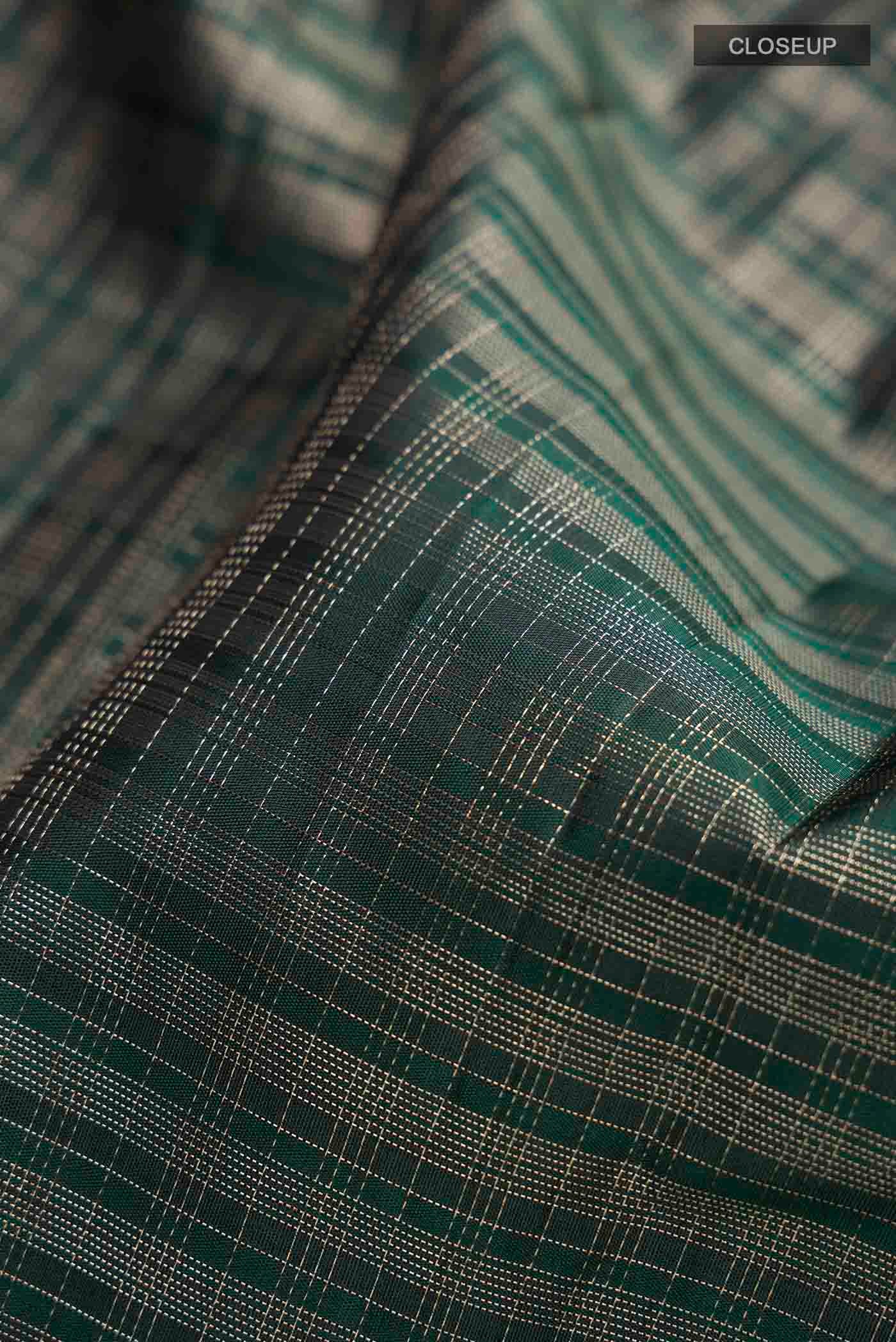 Close up of Green Kanchipuram Silk Saree with Checked design on the body and Zari Border displaying folds