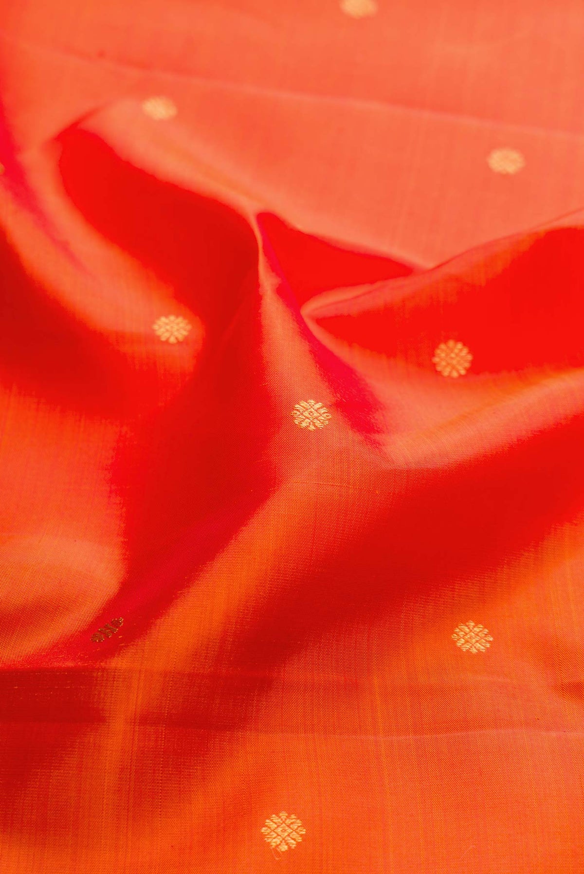 Close up of Orange Dual Tone Kanchipuram Silk Saree with Zari Butta on the body and Zari Border displaying folds