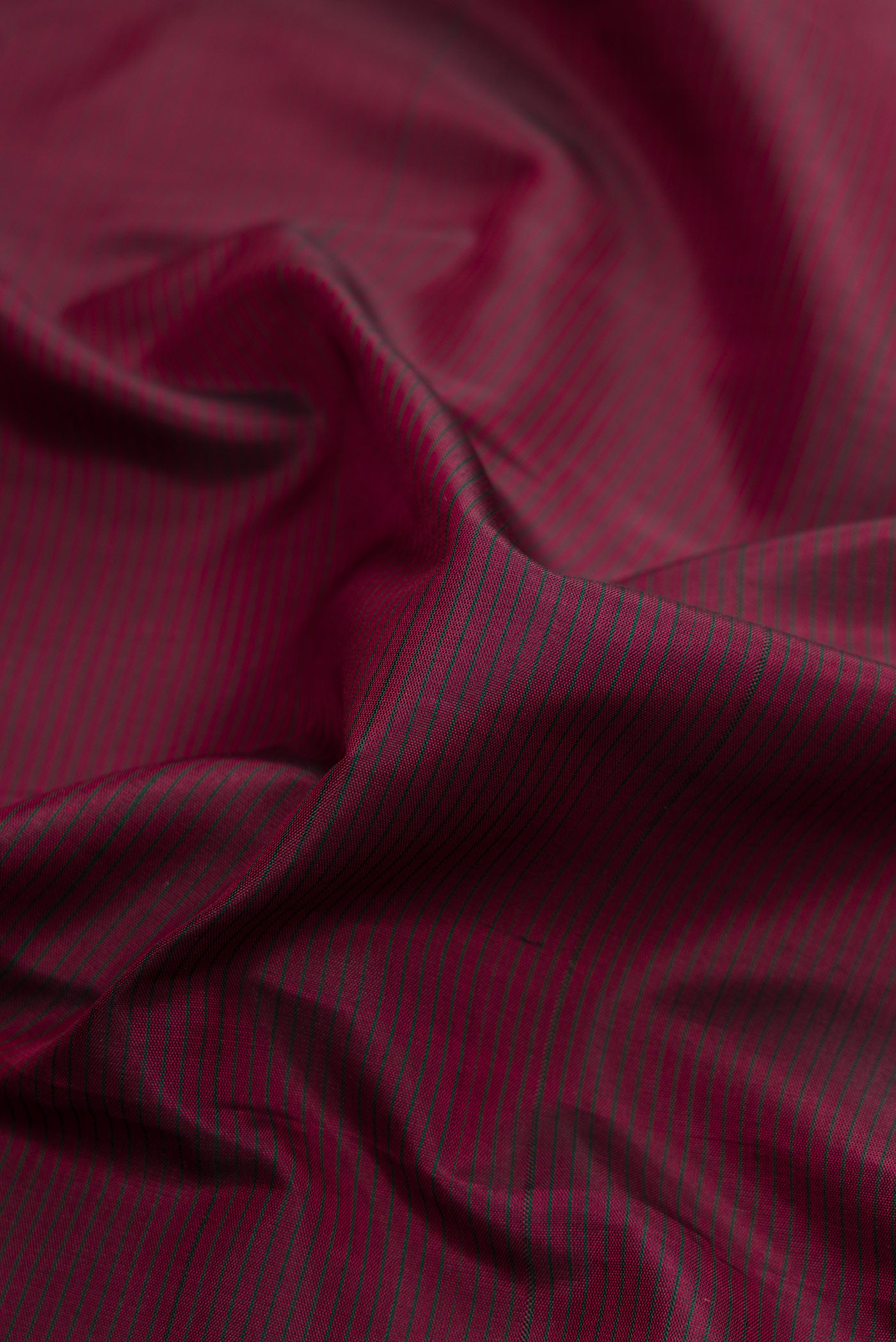 Close up of Maroon Dual Tone Kanchipuram Silk Saree with Stripes on the body and Zari Border.  displaying folds