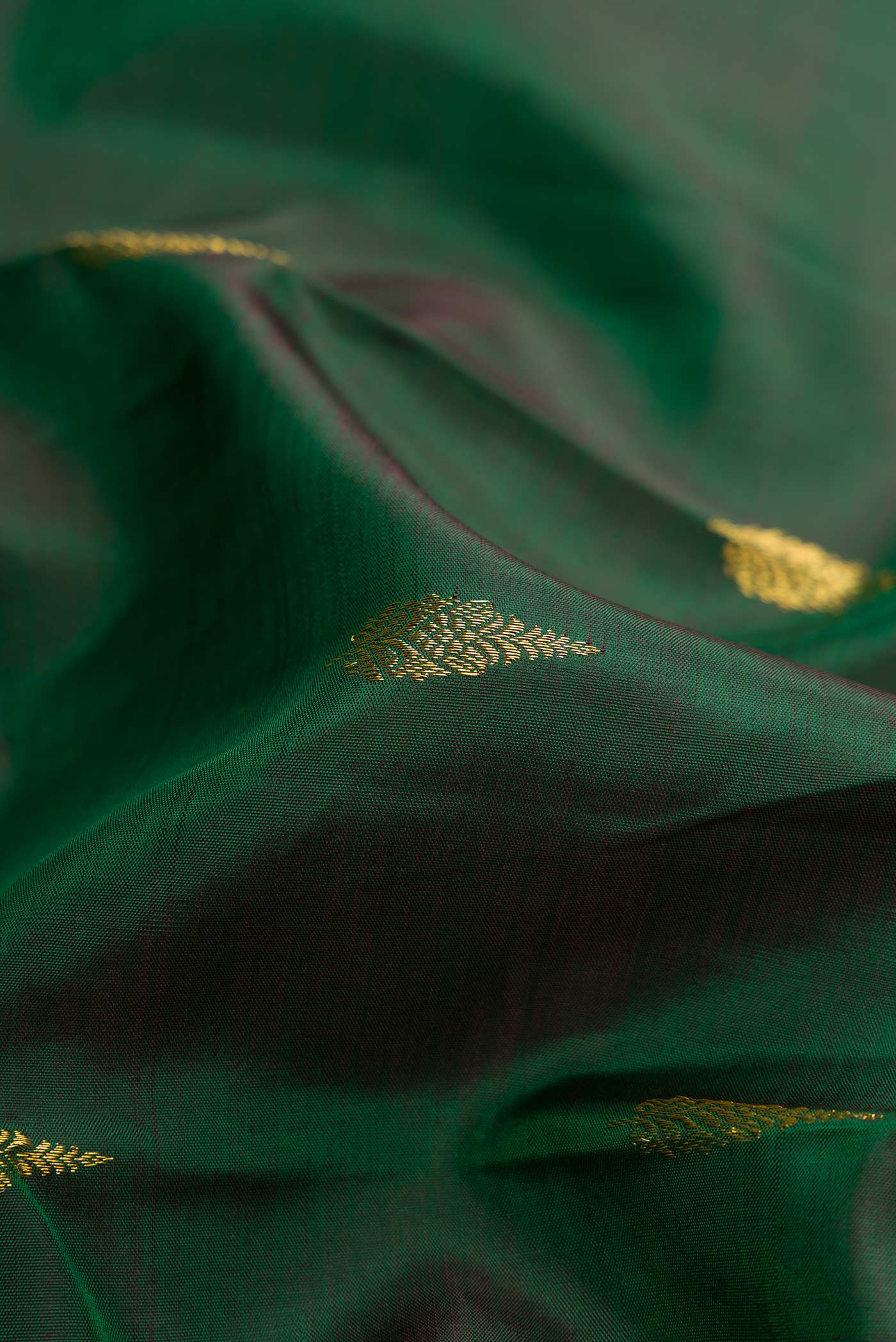 Close up of Green Dual Tone Kanchipuram Silk Saree with Zari Butta on the body and Zari Border displaying folds