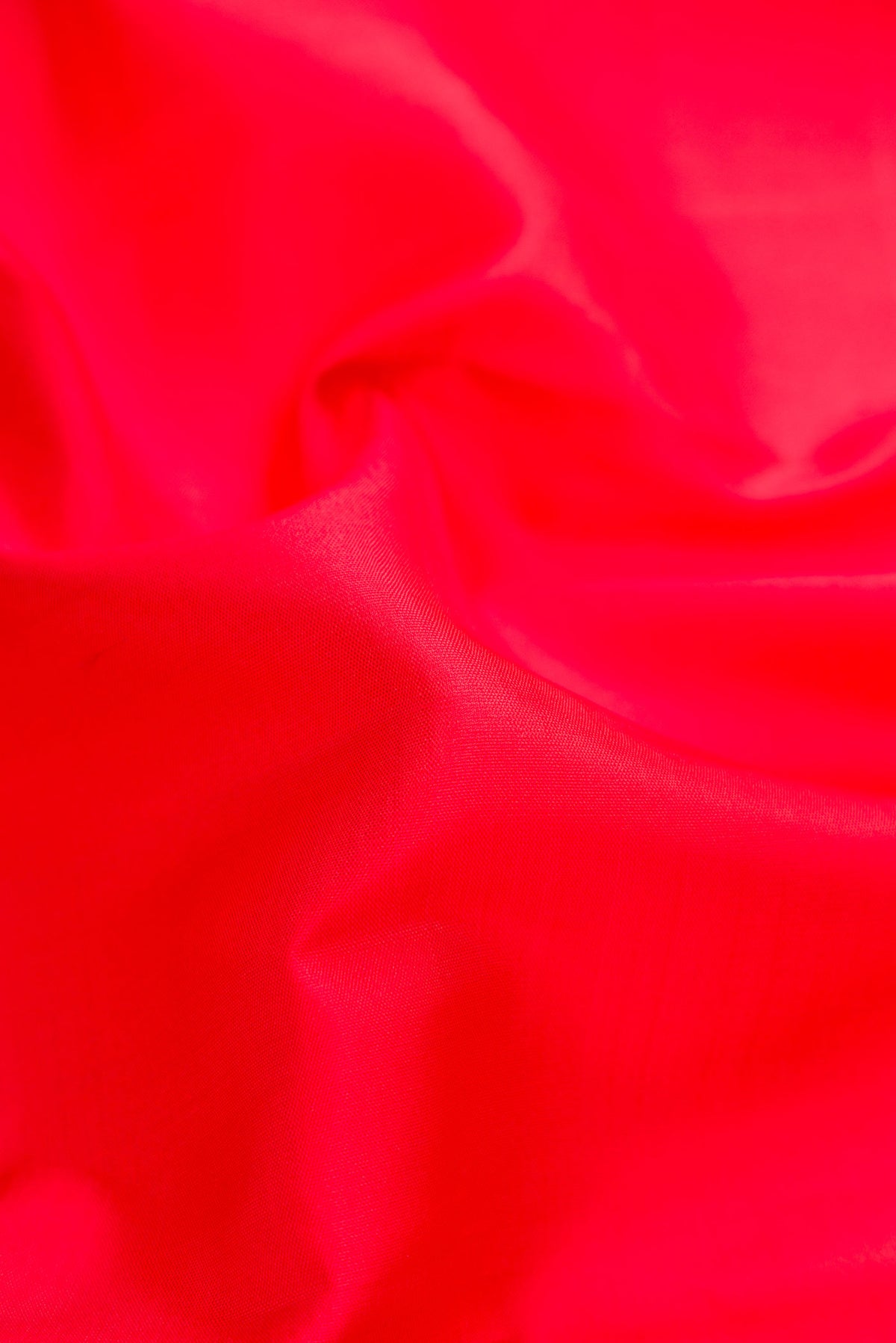 Close up of Red Dual Tone Kanjivaram Silk Saree with Plain Body and Zari Border.  displaying folds