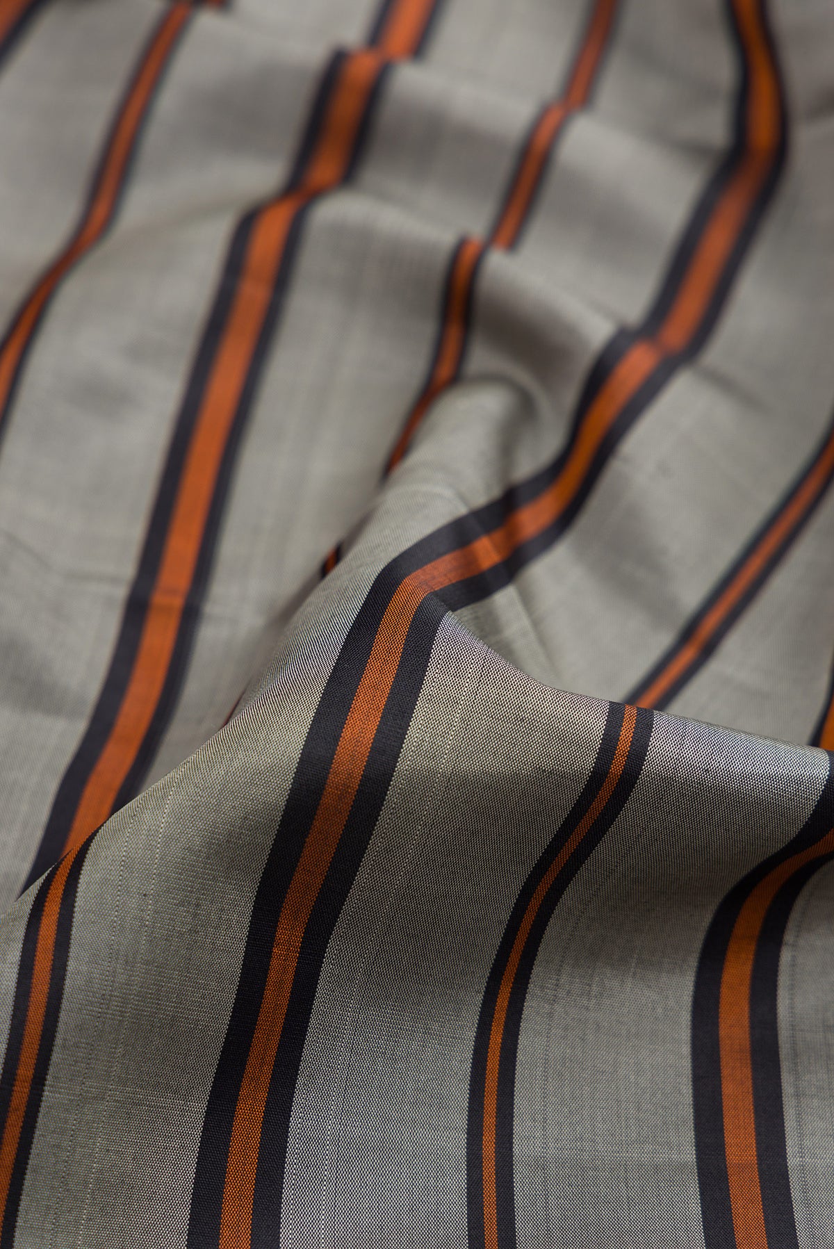 Close up of Grey Dual Tone Kanjivaram Silk Saree with Stripes on the body and Plain Border.  displaying folds